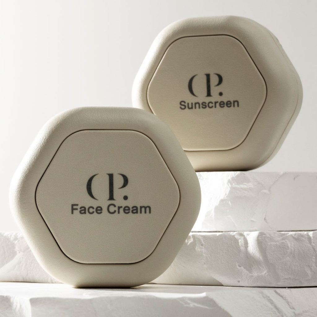 Two capsules displayed on an organic rock background. The capsule closest to the camera has a label reading "CP. | Face Cream" and the capsule further from the camera has a label reading "CP. | Sunscreen"
