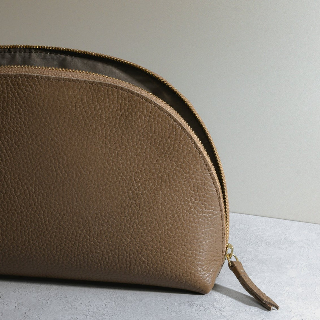 Travel case resting on a gray background with the zipper slightly open 