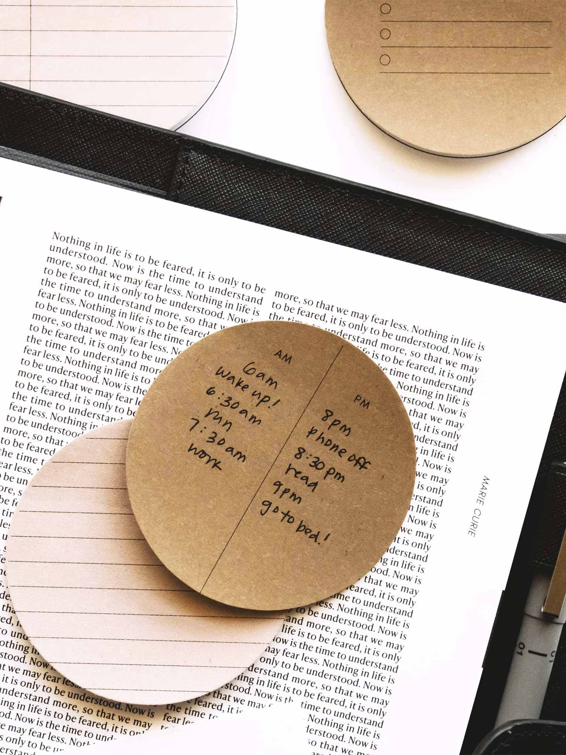 Printed circle sticky notes in use inside a leather planner cover with Uni Pin in planner's pen loop.