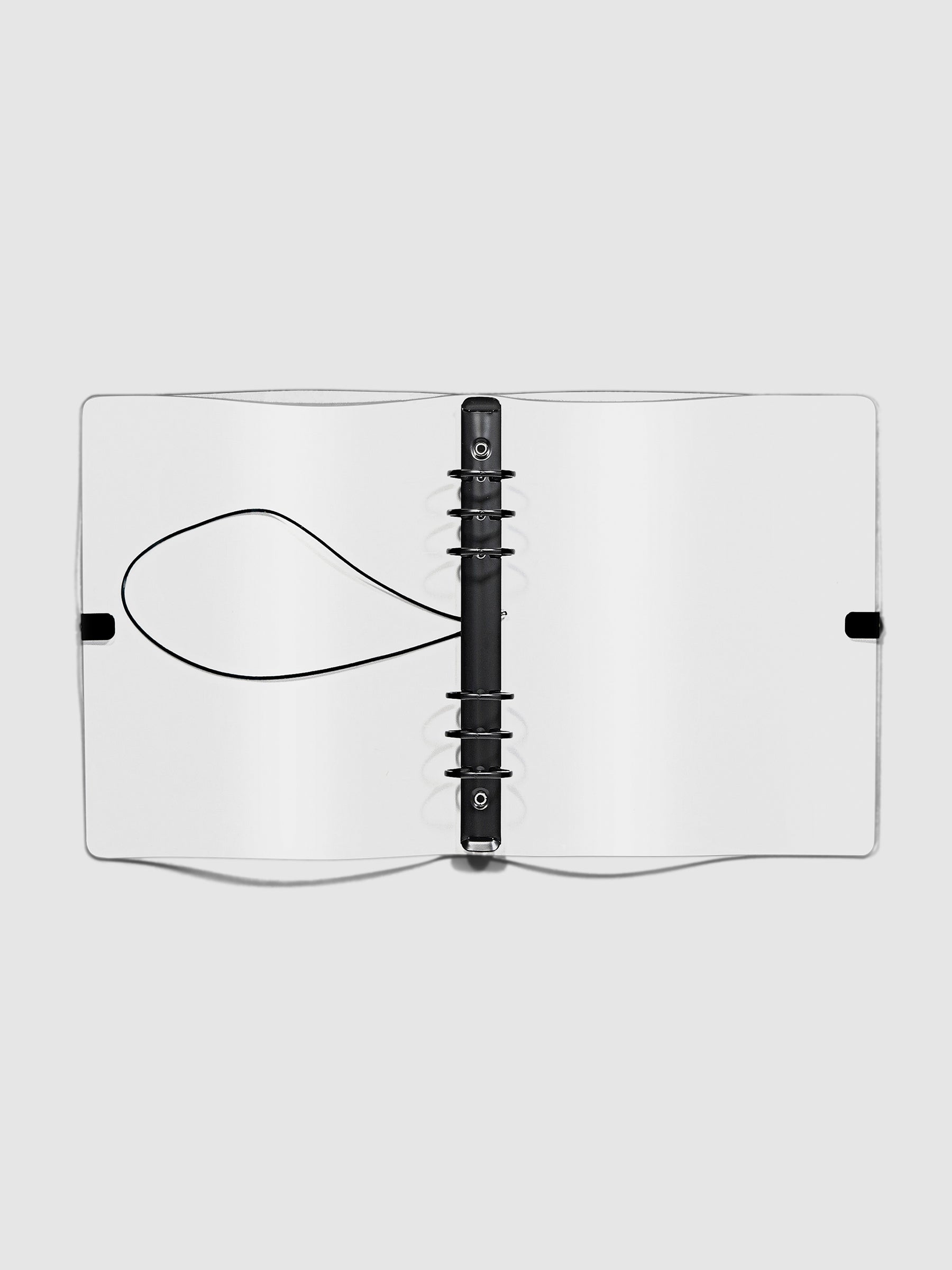 Open clear vinyl 6 ring agenda with black bungee shown open on a neutral background.