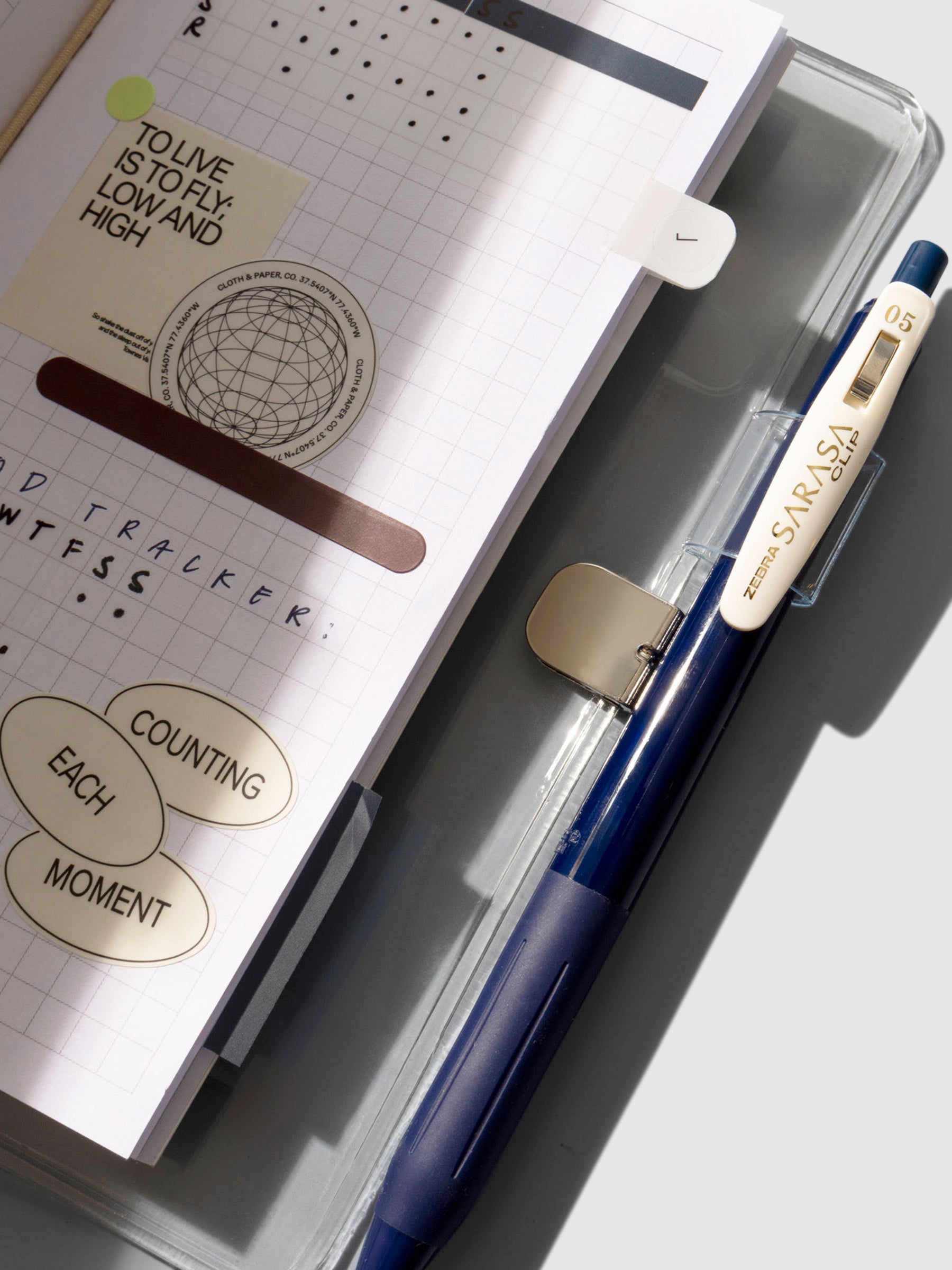 Closeup of cover shown open with a Travel Notebook and Zebra Sarasa Clip pen inside of it.