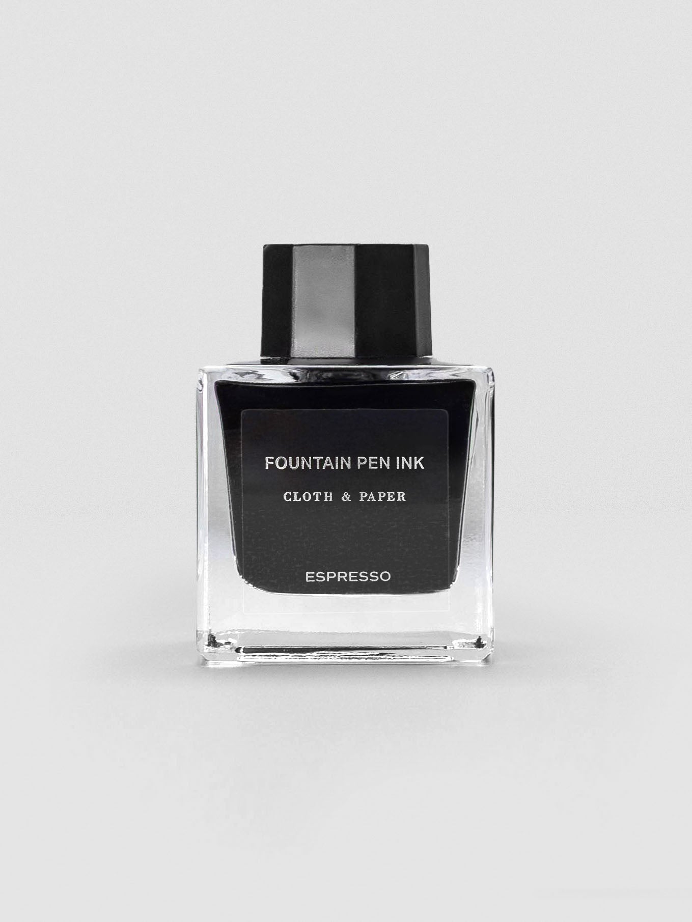 A square glass bottle of Cloth & Paper Fountain Pen Ink in Espresso, sealed with a black cap.