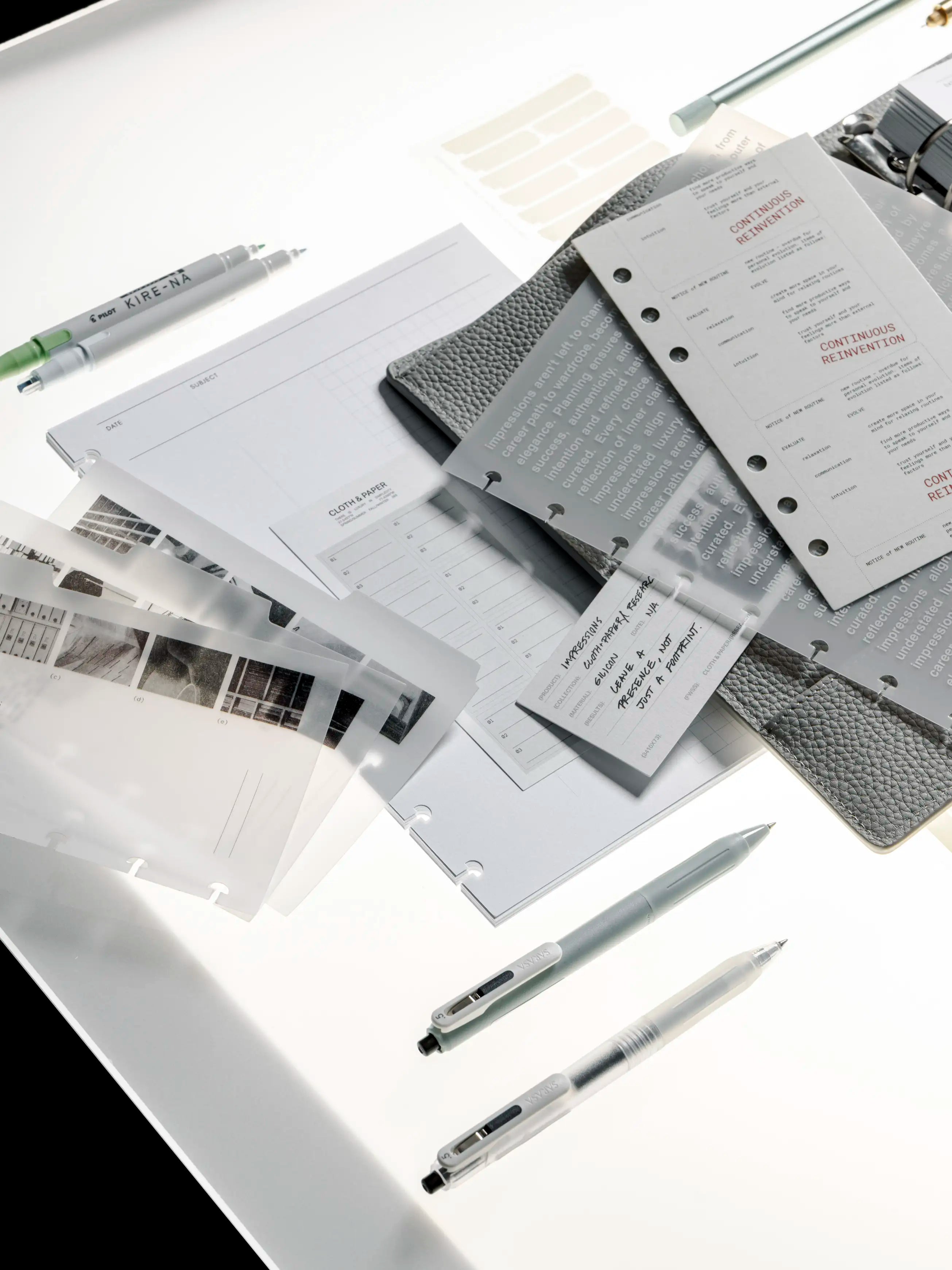 Collection of stationery items including pens, notebooks, and planner dashboards on a white surface.