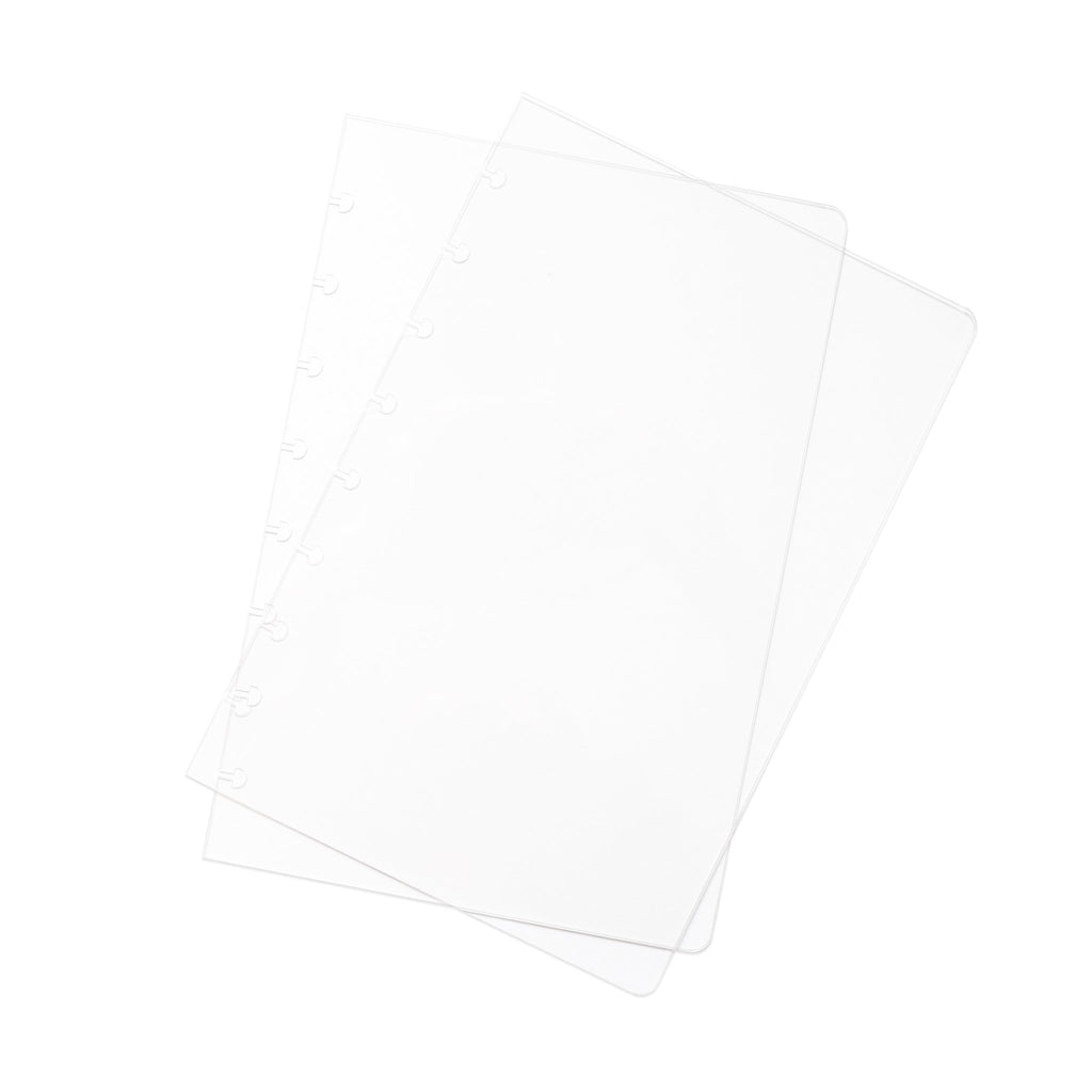 Crystal Clear Discbound Notebook Cover, Half Letter, Cloth and Paper. Two transparent notebook covers laid on top of one another with the top cover tilted slightly to the right.