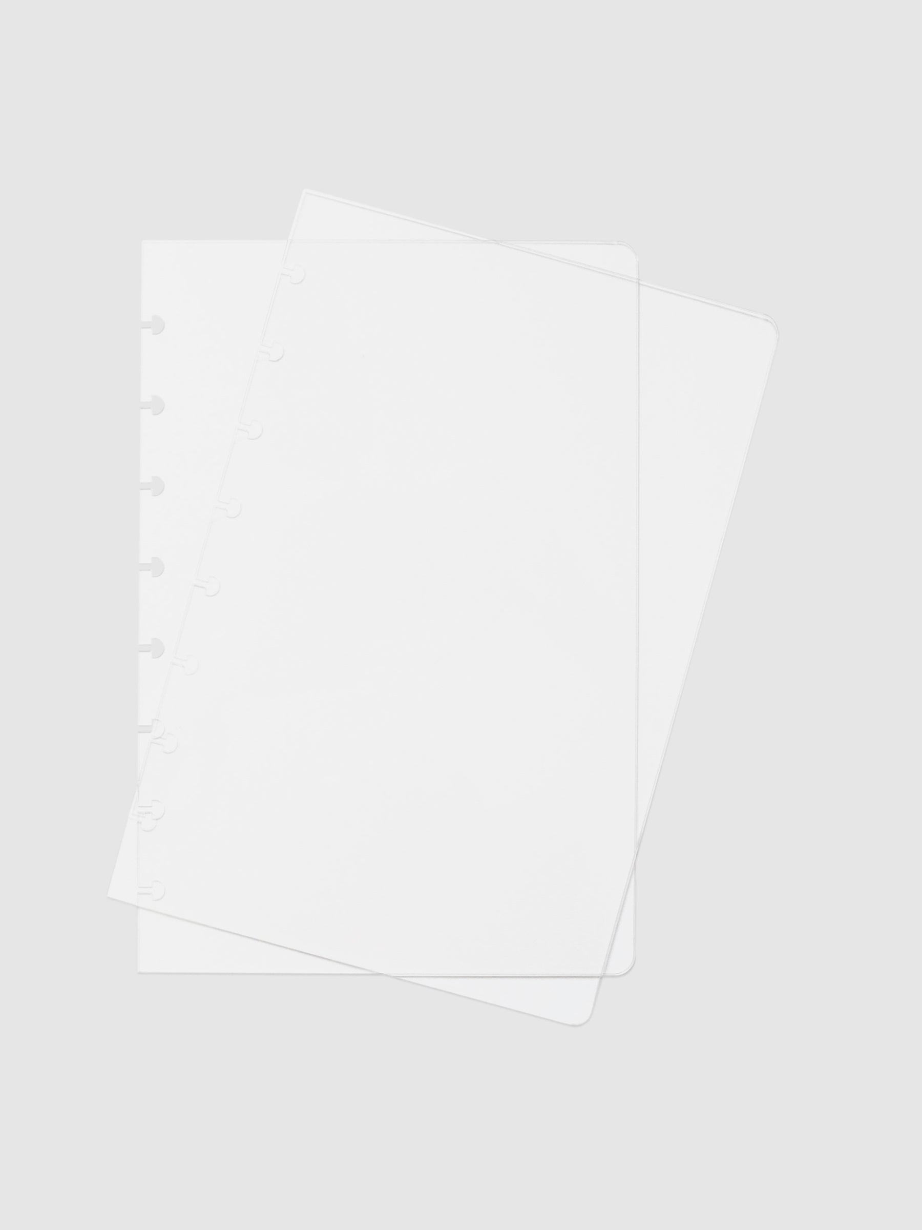 Crystal Clear Discbound Notebook Cover, Half Letter, Cloth and Paper. Two transparent notebook covers laid on top of one another with the top cover tilted slightly to the right.