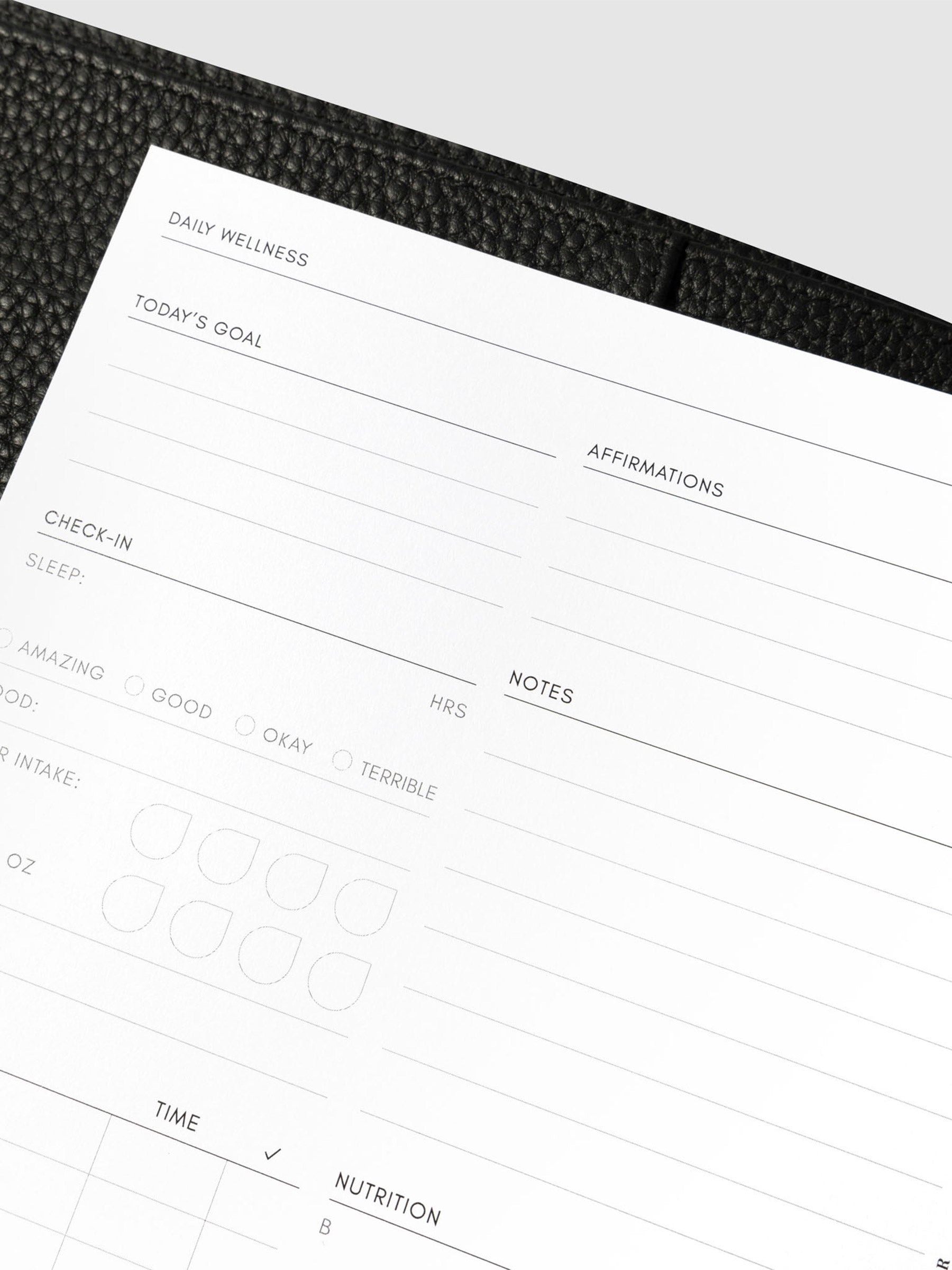 Closeup of daily wellness page inside a black leather planner.