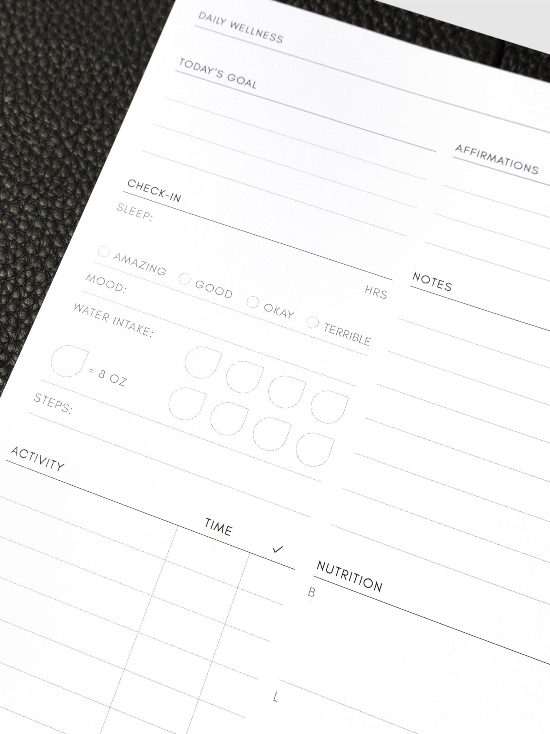 Closeup of daily wellness page inside a black leather planner.