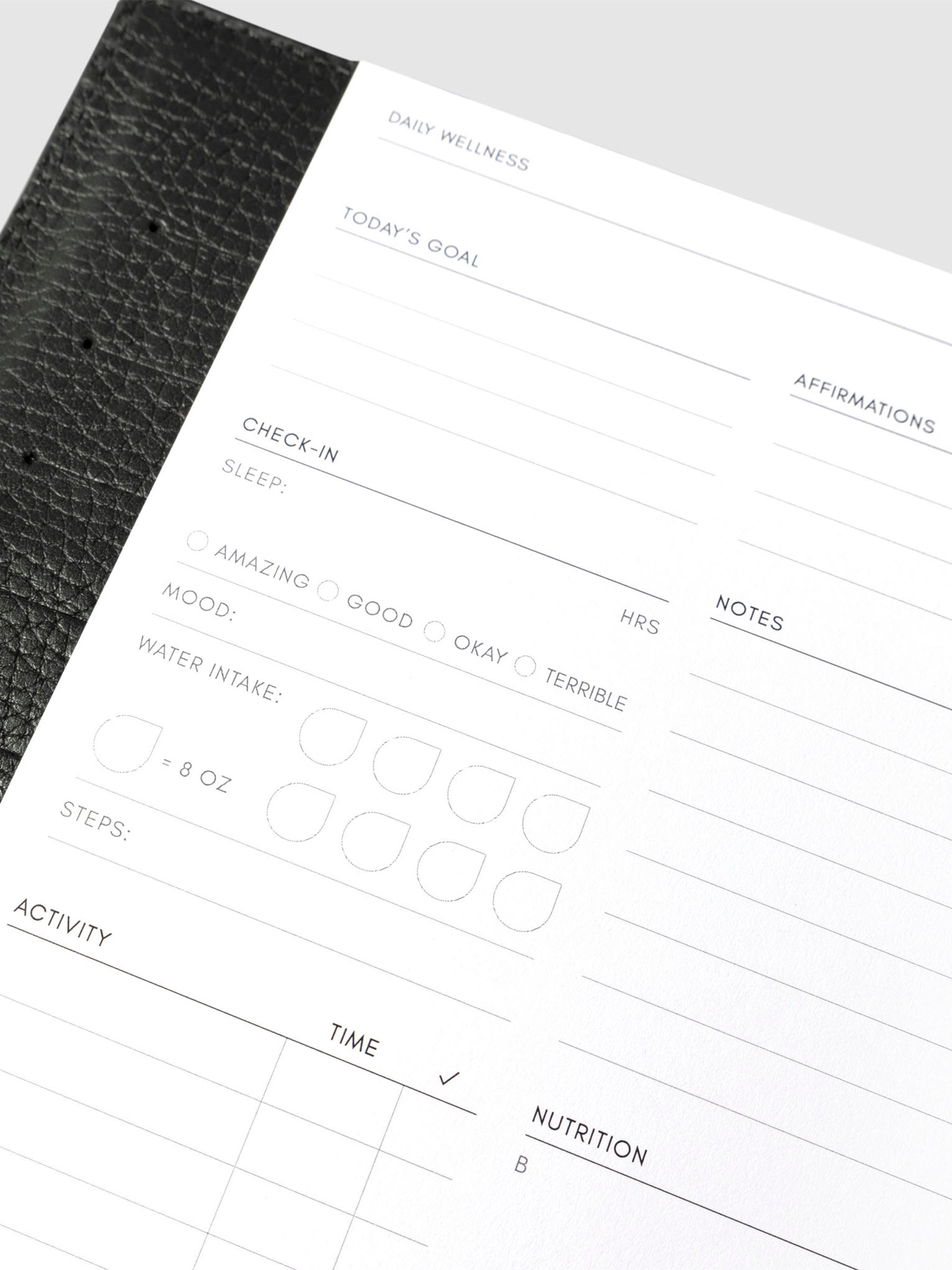 Closeup of daily wellness page inside a black leather planner.