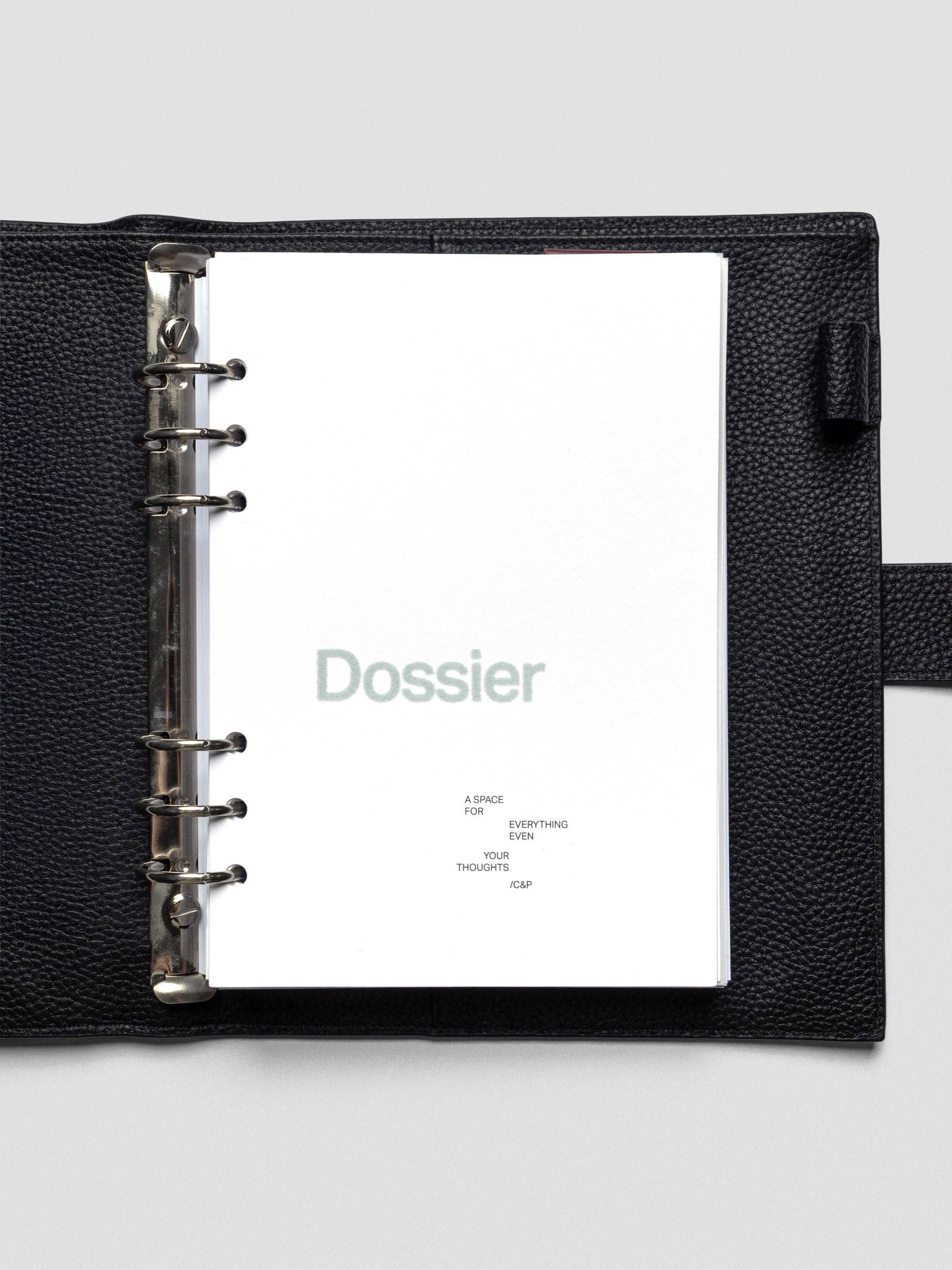 White cardstock planner dashboard with "Dossier" text in a green-blue flocked material with text below in A5 size shown in a leather planner cover.