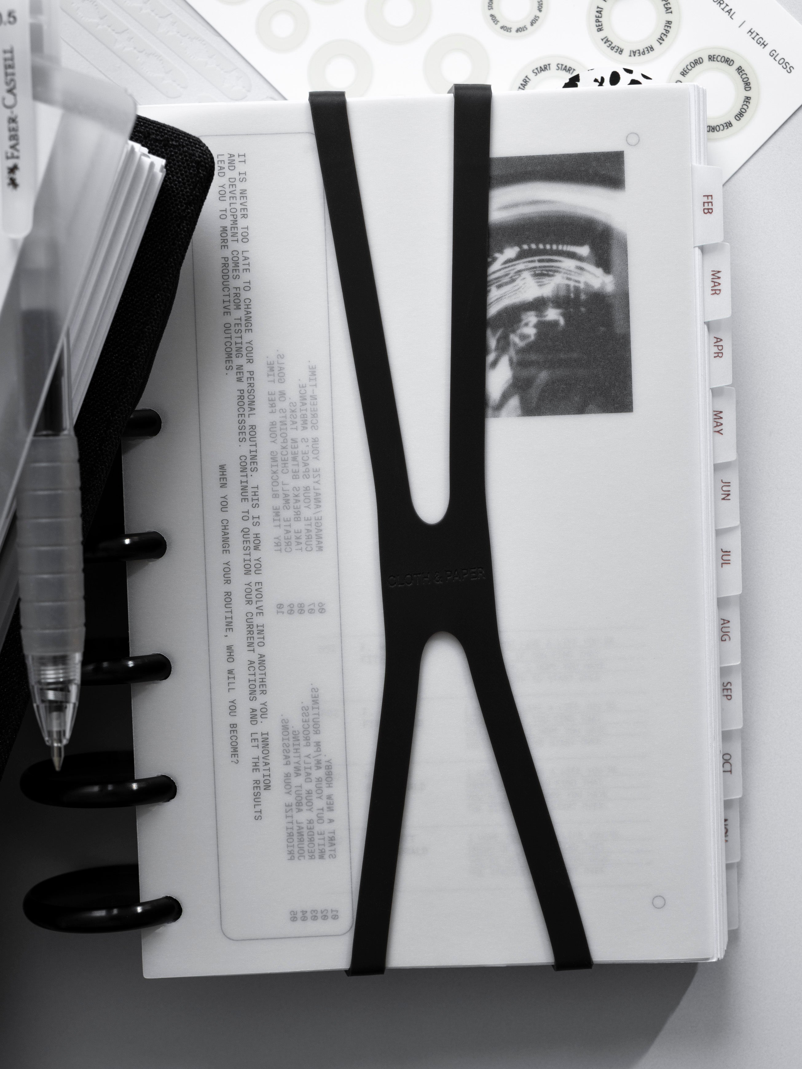 Discbound Cloth & Paper planner with a black band secured around it on a white background