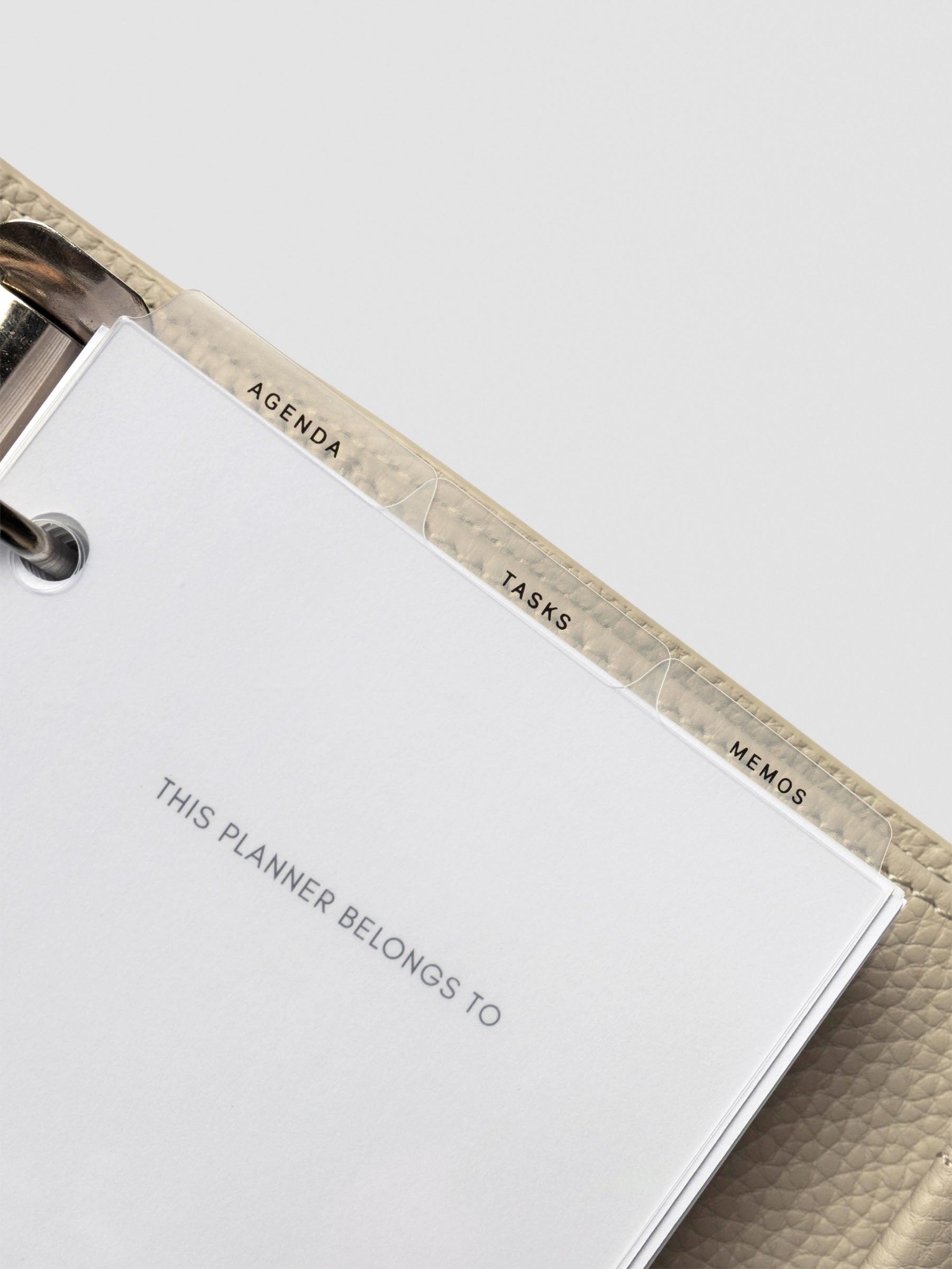 Ultra-thin clear planner dividers inside a cream leather planner, tabs labeled Agenda, Tasks, and Memos aligned neatly above the first page.
