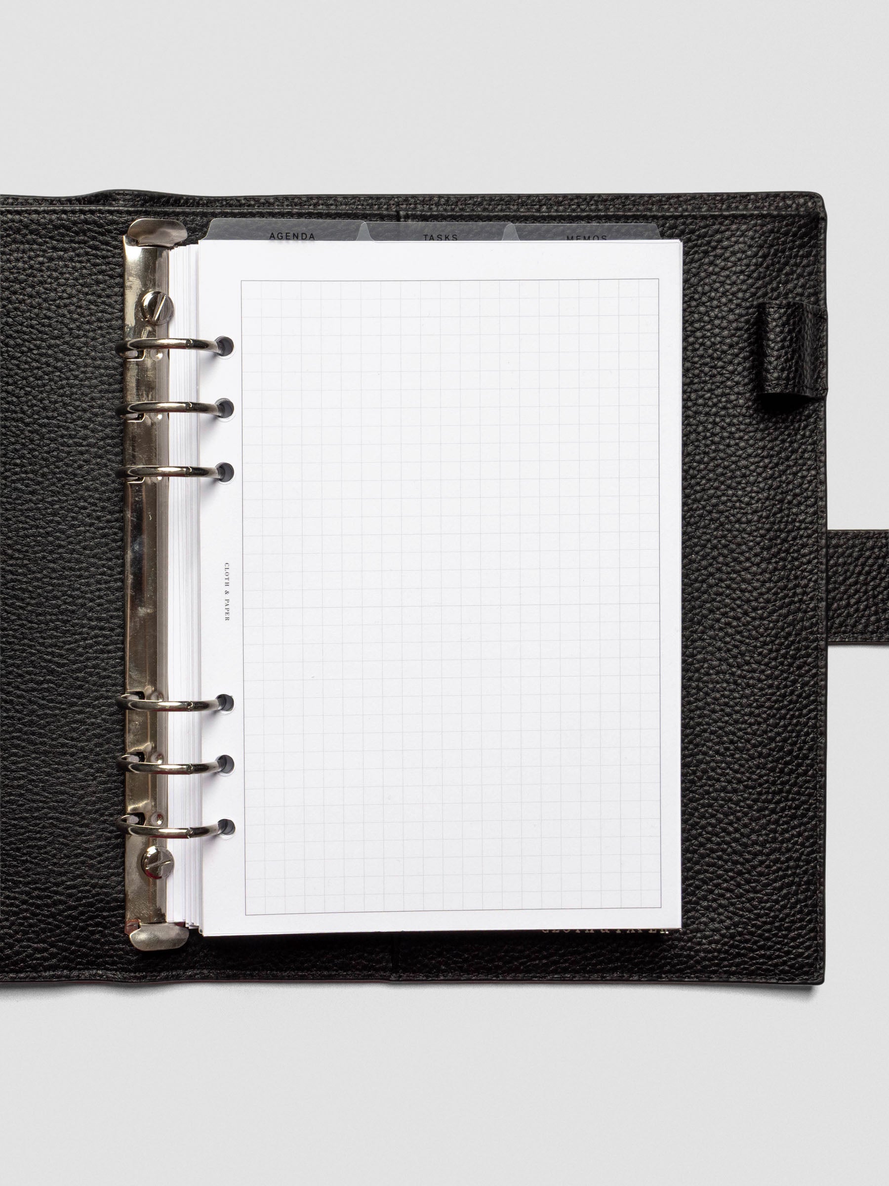 A5 size planner with ultra-thin clear top tab dividers labeled Agenda, Tasks, and Memos. Tabs are visible above a grid notes page.