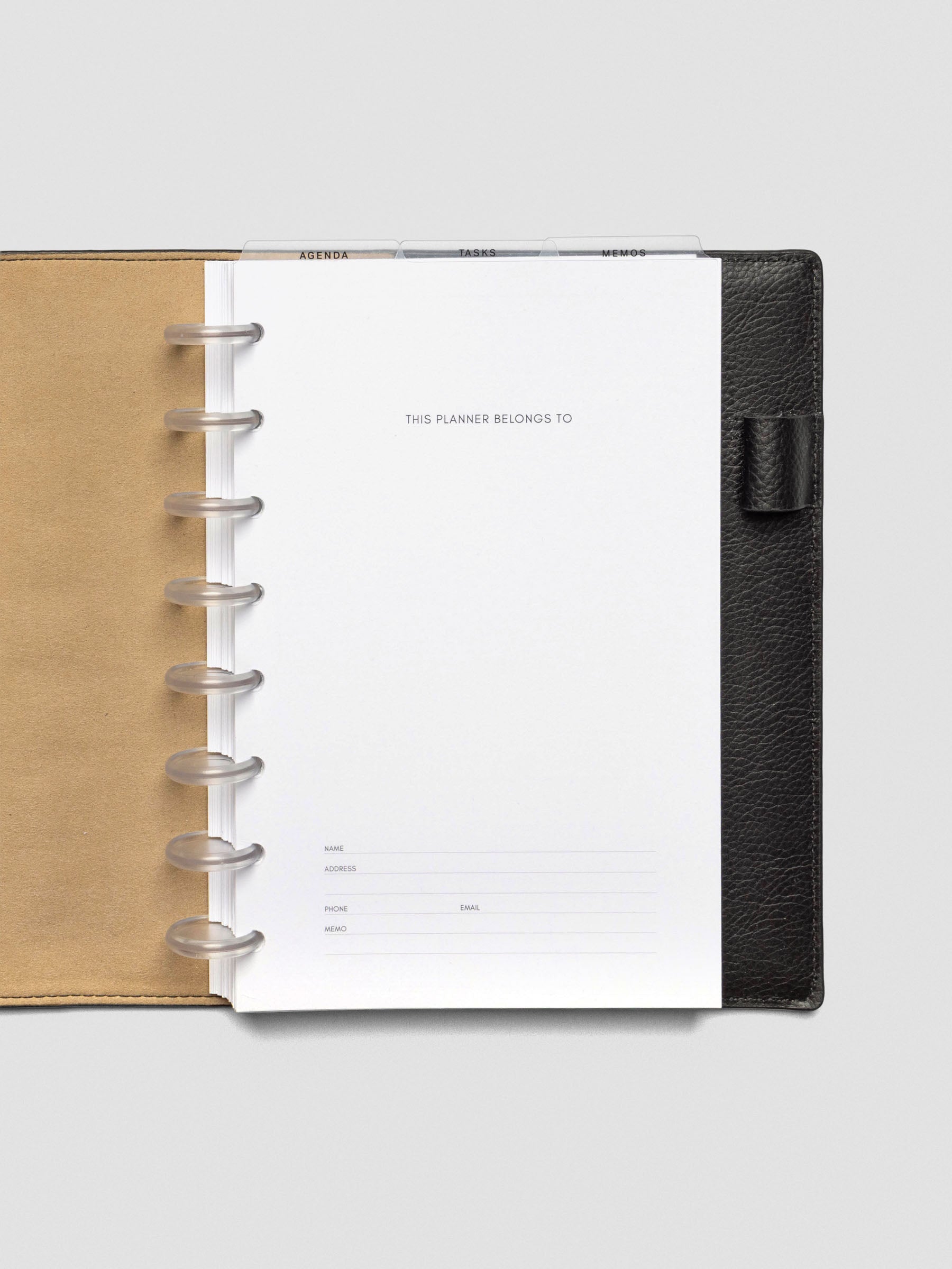 Half-letter planner with ultra-thin clear top tab dividers labeled Agenda, Tasks, and Memos. Tabs extend above the title page inside a black leather planner.