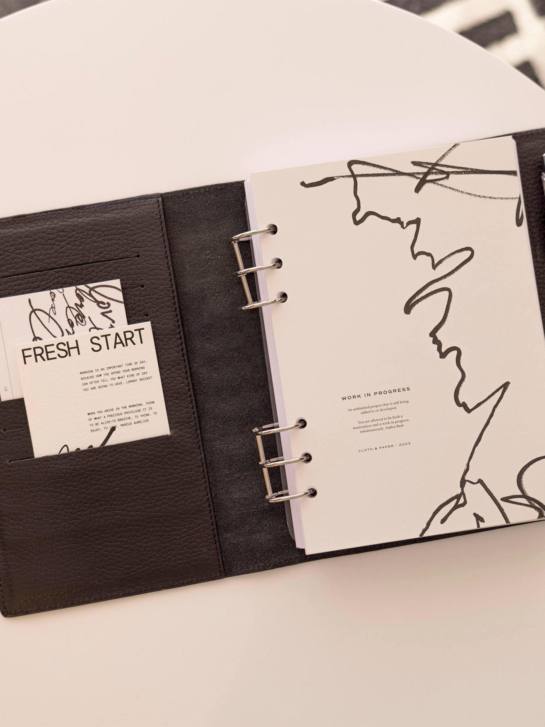 Half Letter/A5 6-Ring cover displayed inside a black leather folio with silver rings. Size shown is A5 6-Ring.