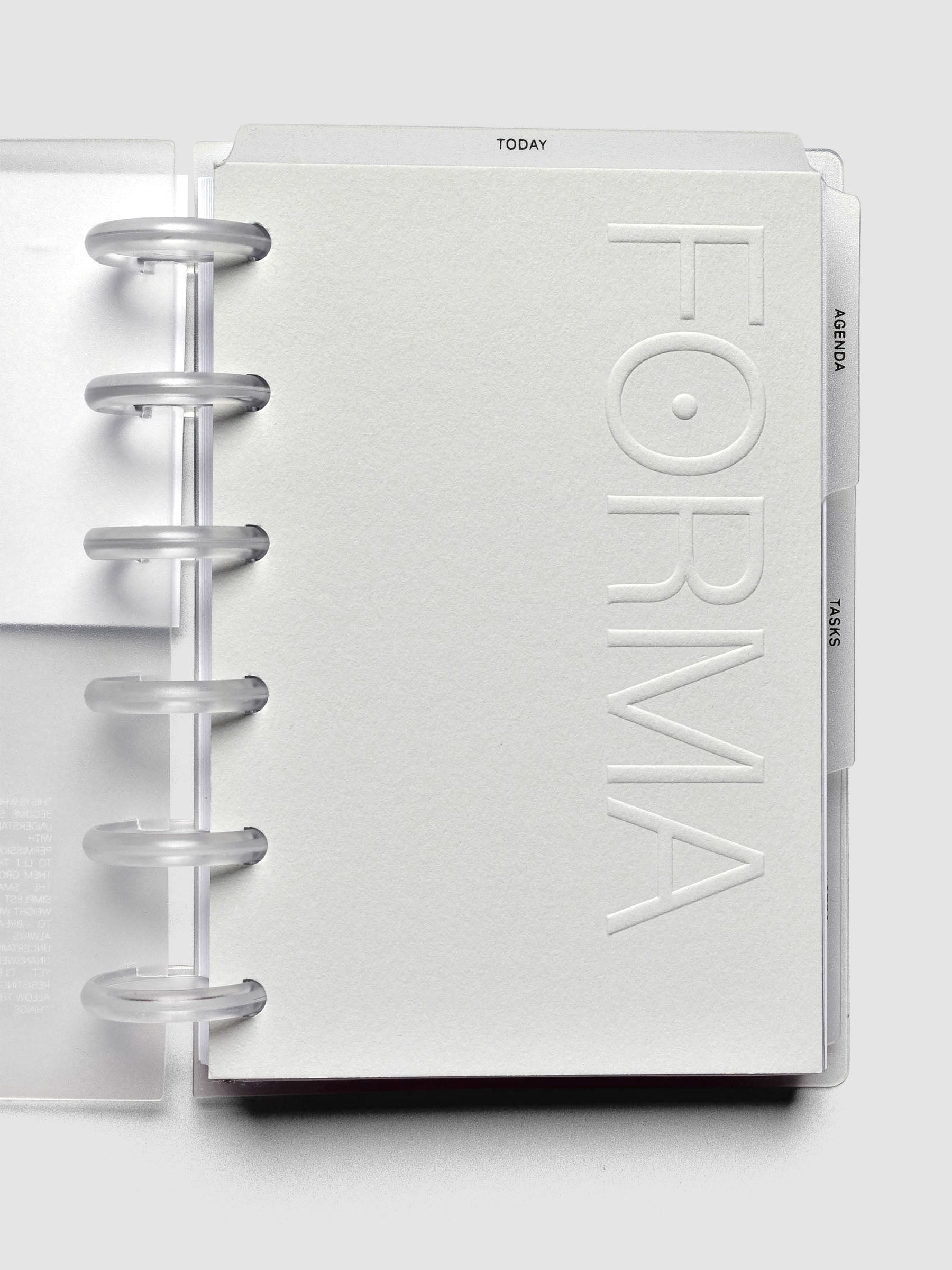 Open 6-disc planner showing a light neutral cardstock planner dashboard with embossed text reading "FORMA".