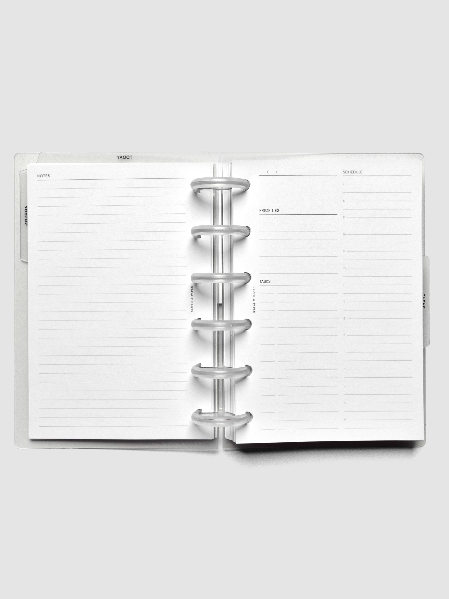 Open discbound planner displaying a lined notes page and an undated daily schedule page.