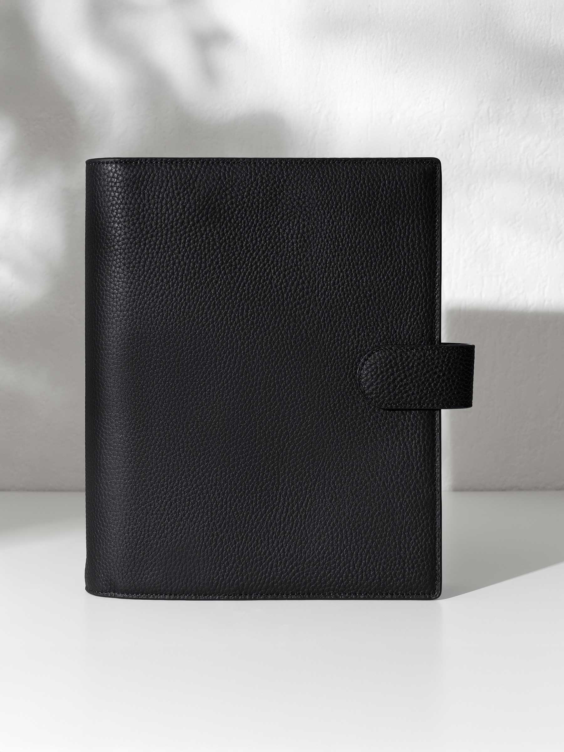 Black leather agenda displayed against a shadowed background.