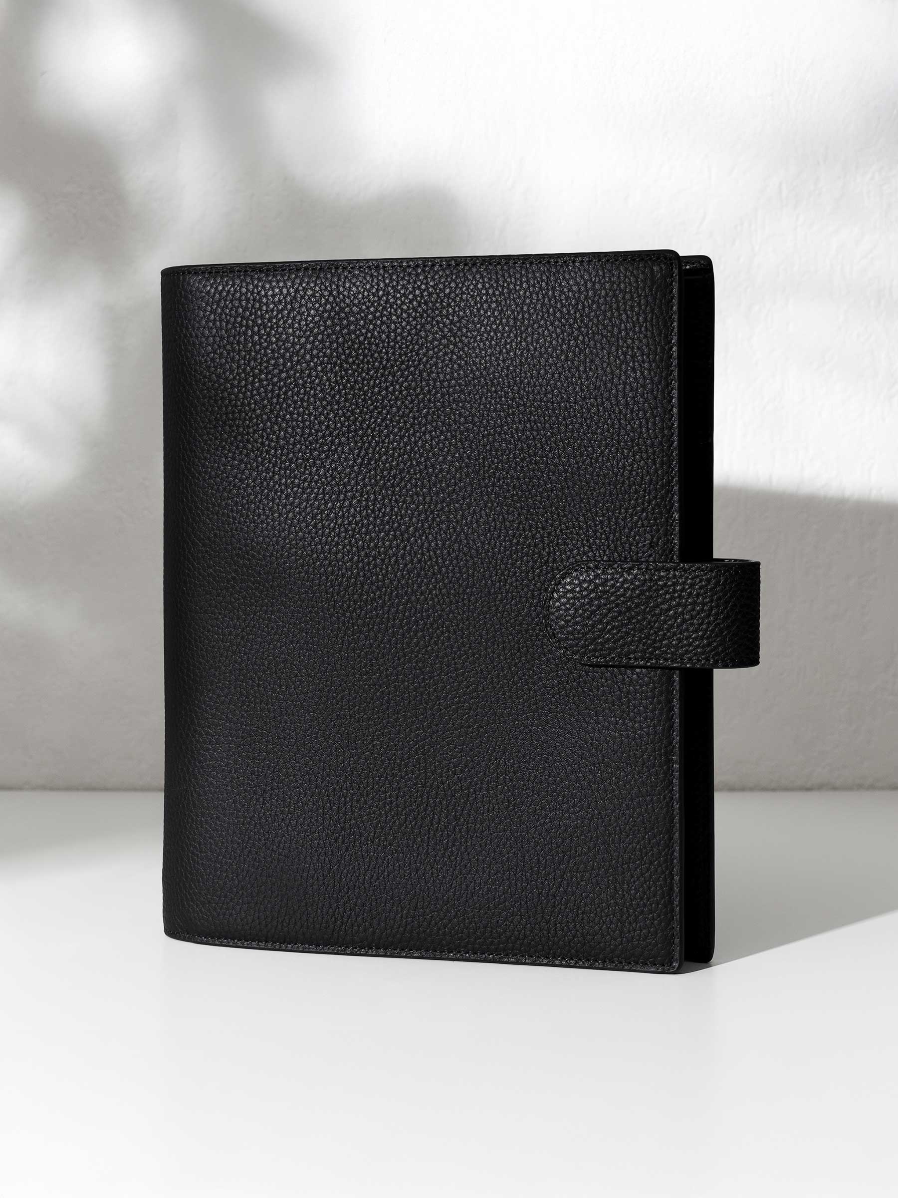 Black leather agenda displayed against a shadowed background.