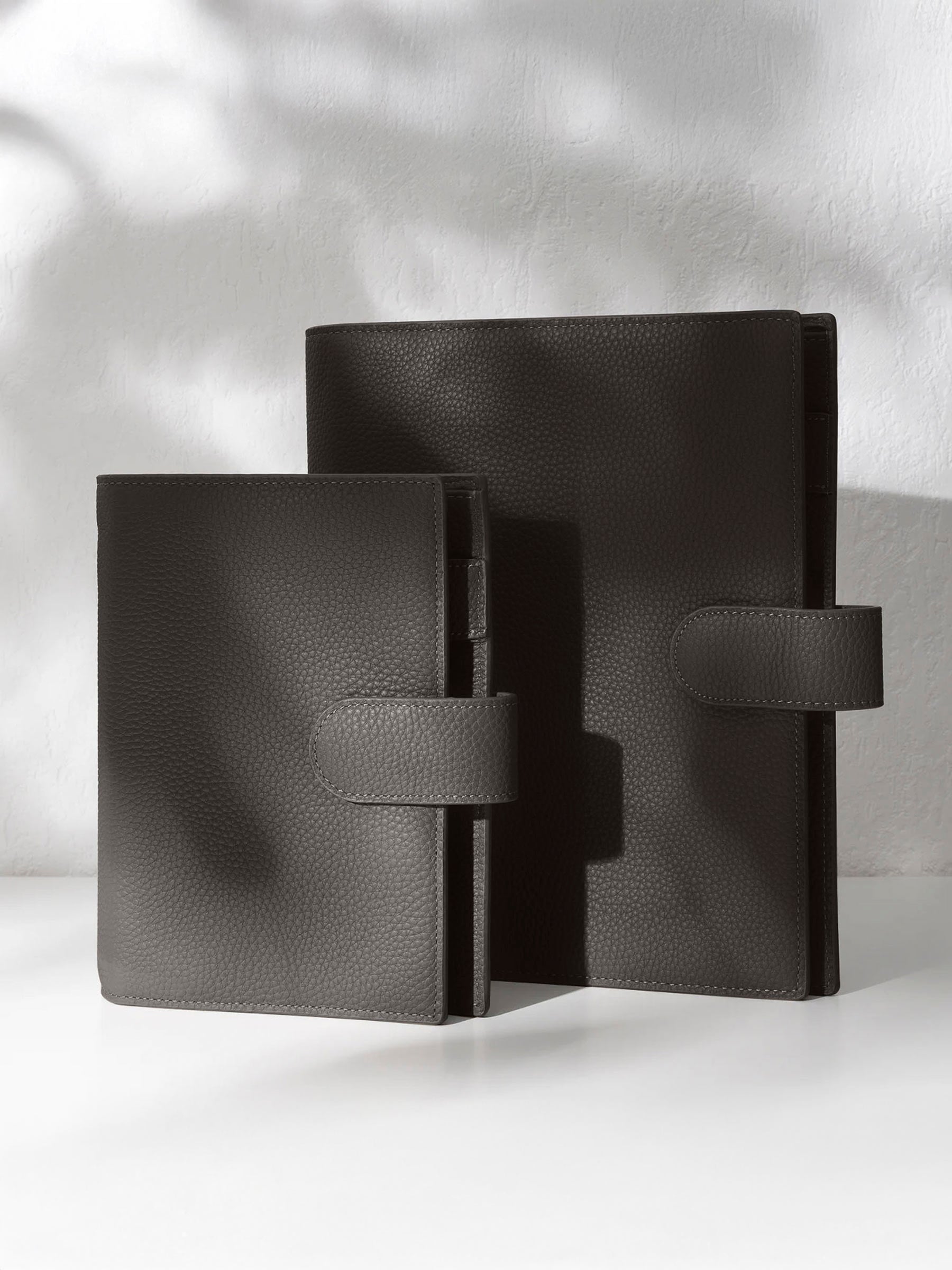 Two cafenoir leather agendas displayed against a shadowed background.