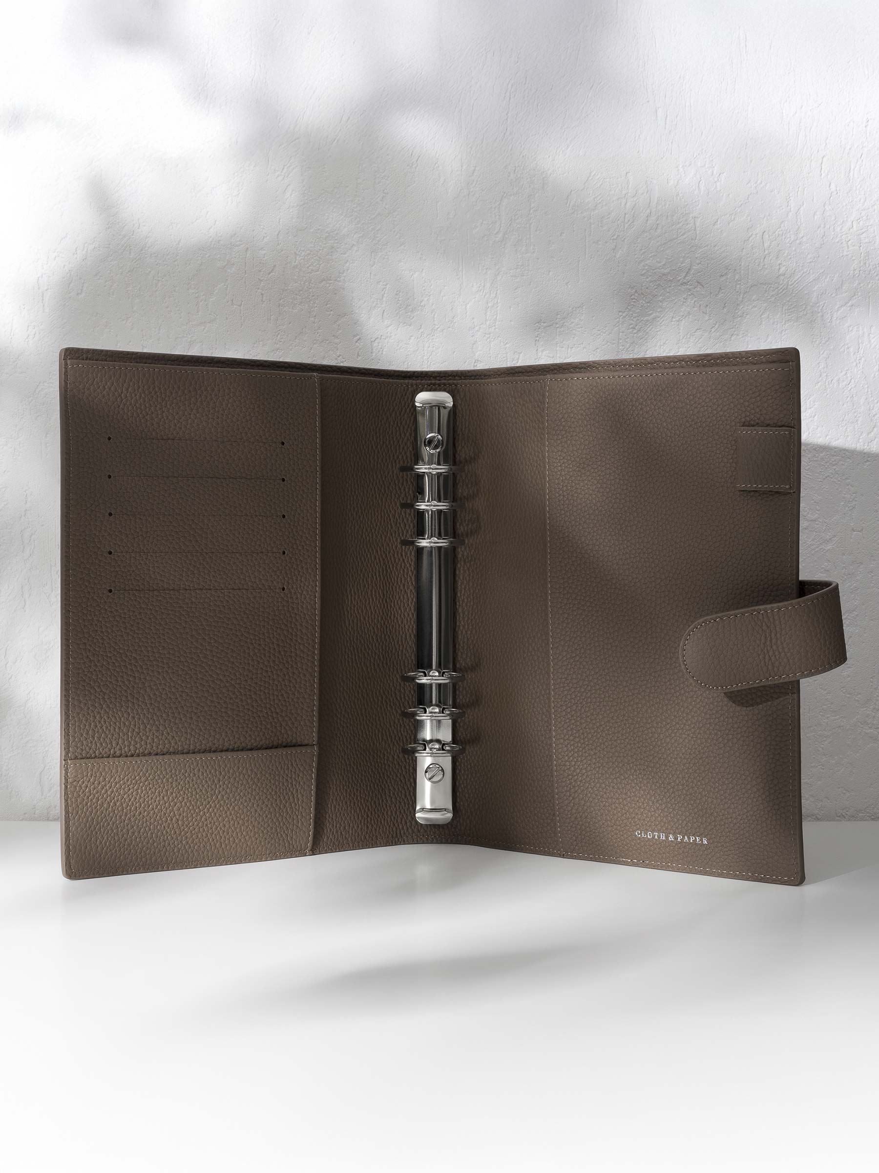 Cortado leather agenda displayed against a shadowed background. It is opened to display the silver hardware and company foil stamp.