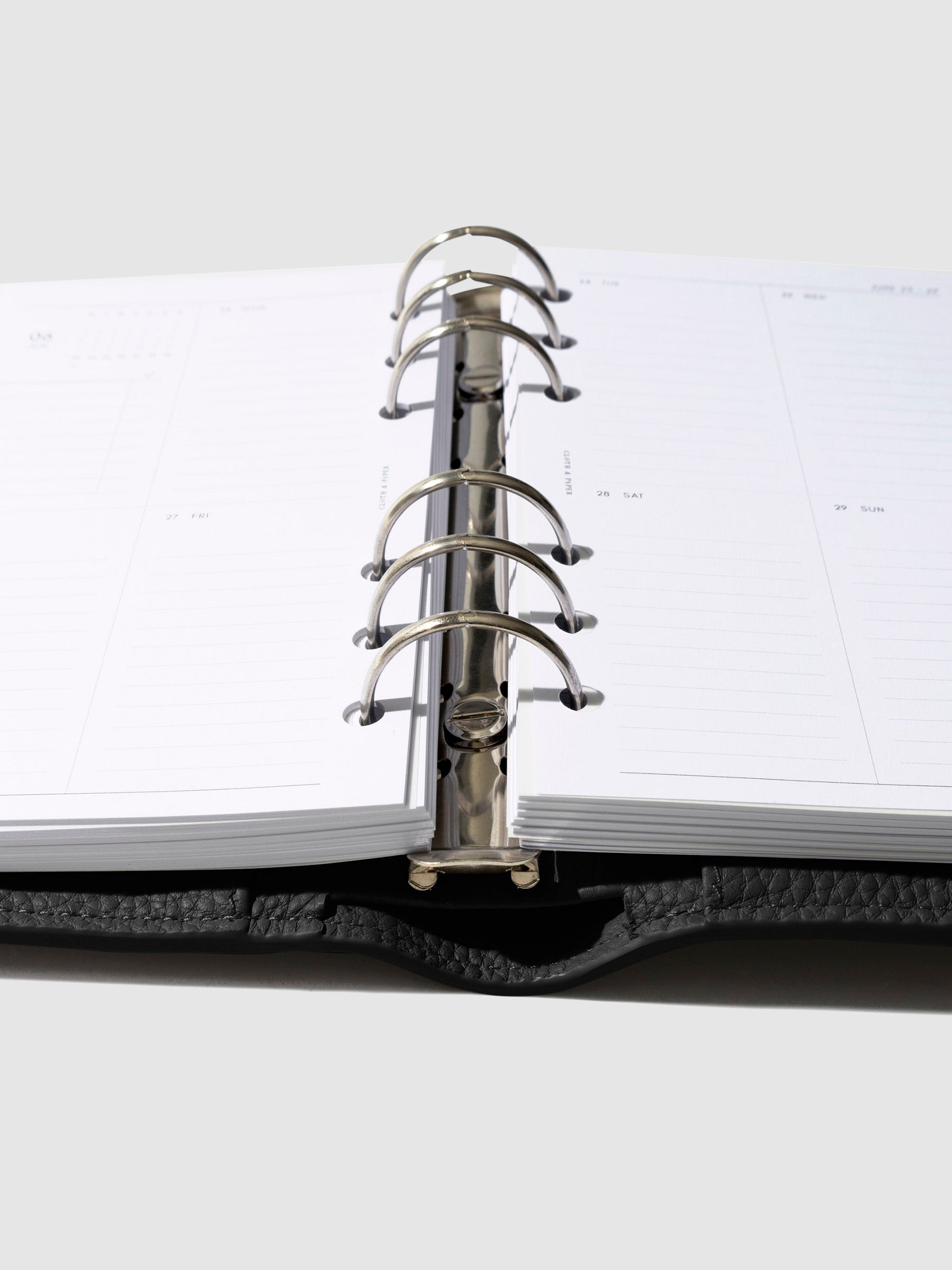 Personal sized planner in a black leather agenda close up of inserts on silver rings.