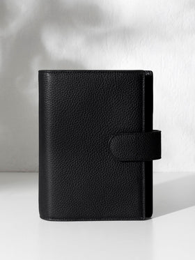 Black leather agenda displayed against a shadowed background.