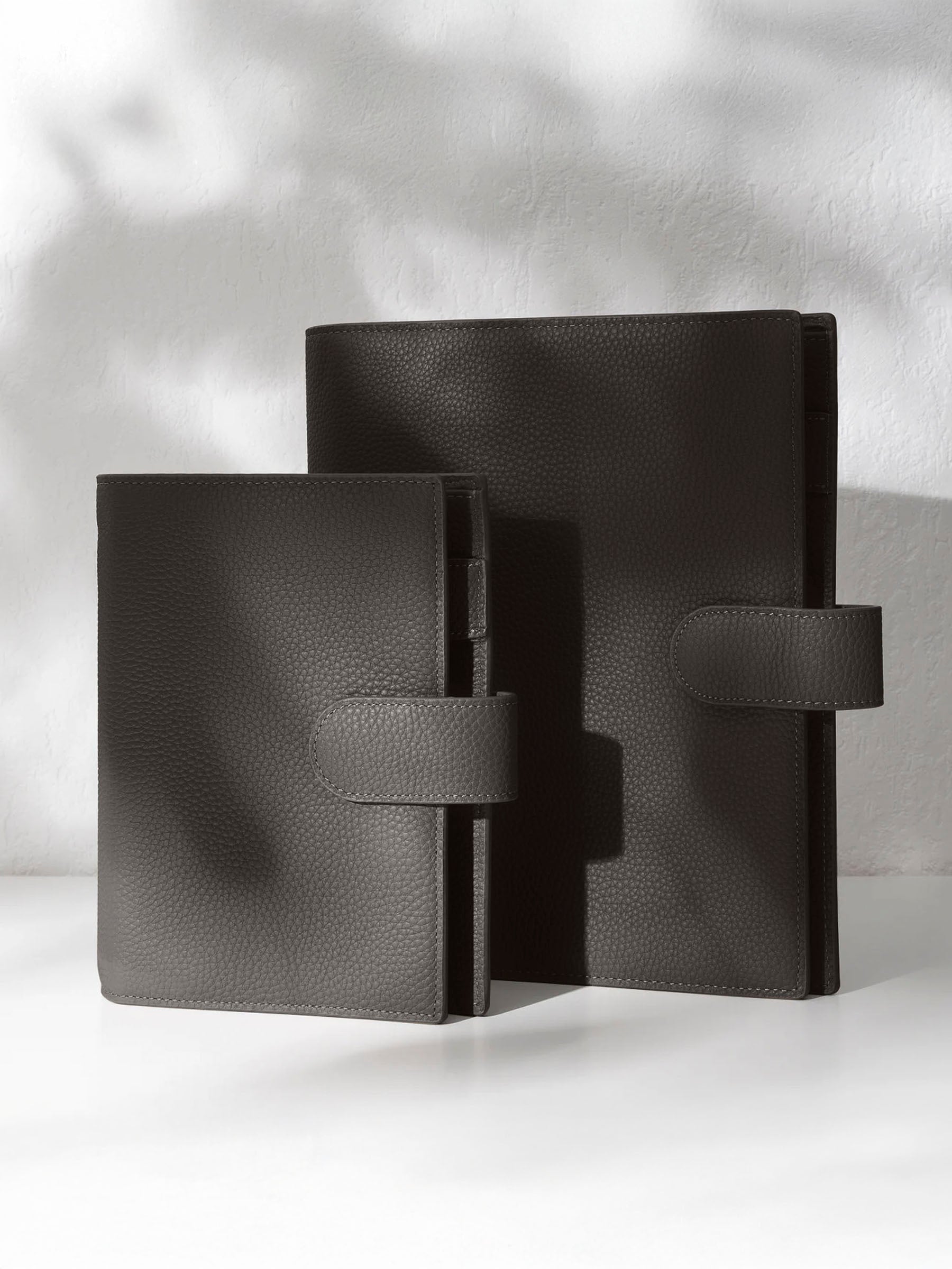 Two cafenoir leather agendas on an off-white background.