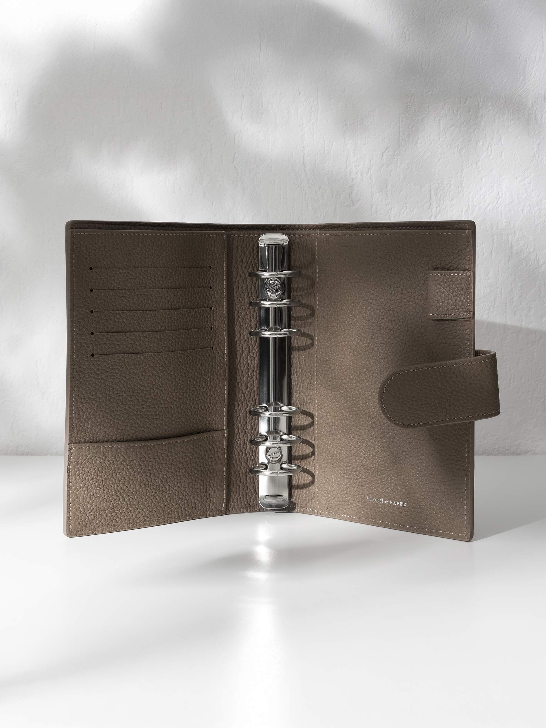 Cortado leather agenda displayed against a shadowed background. It is opened to display the silver hardware and company foil stamp.