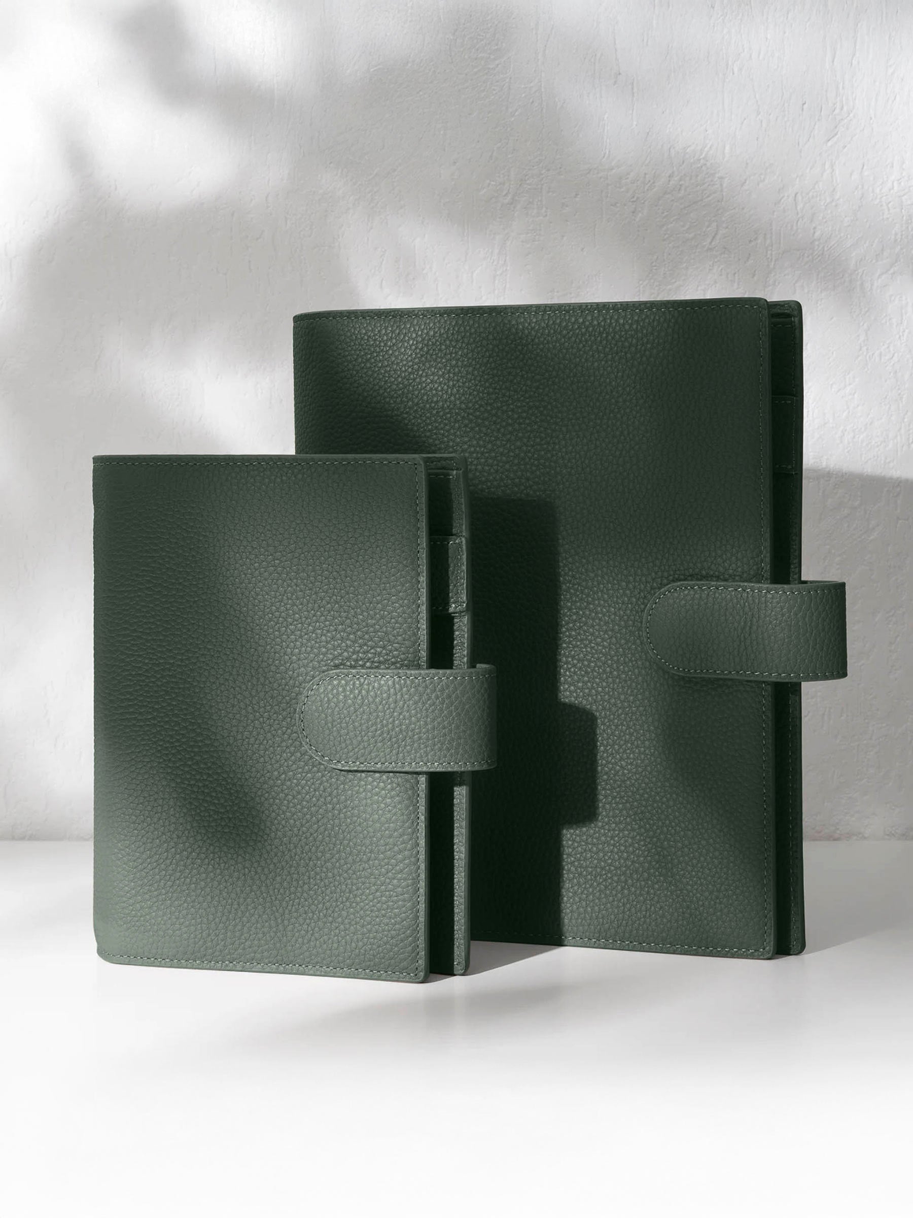 Two cypress leather agendas displayed against a shadowed background.