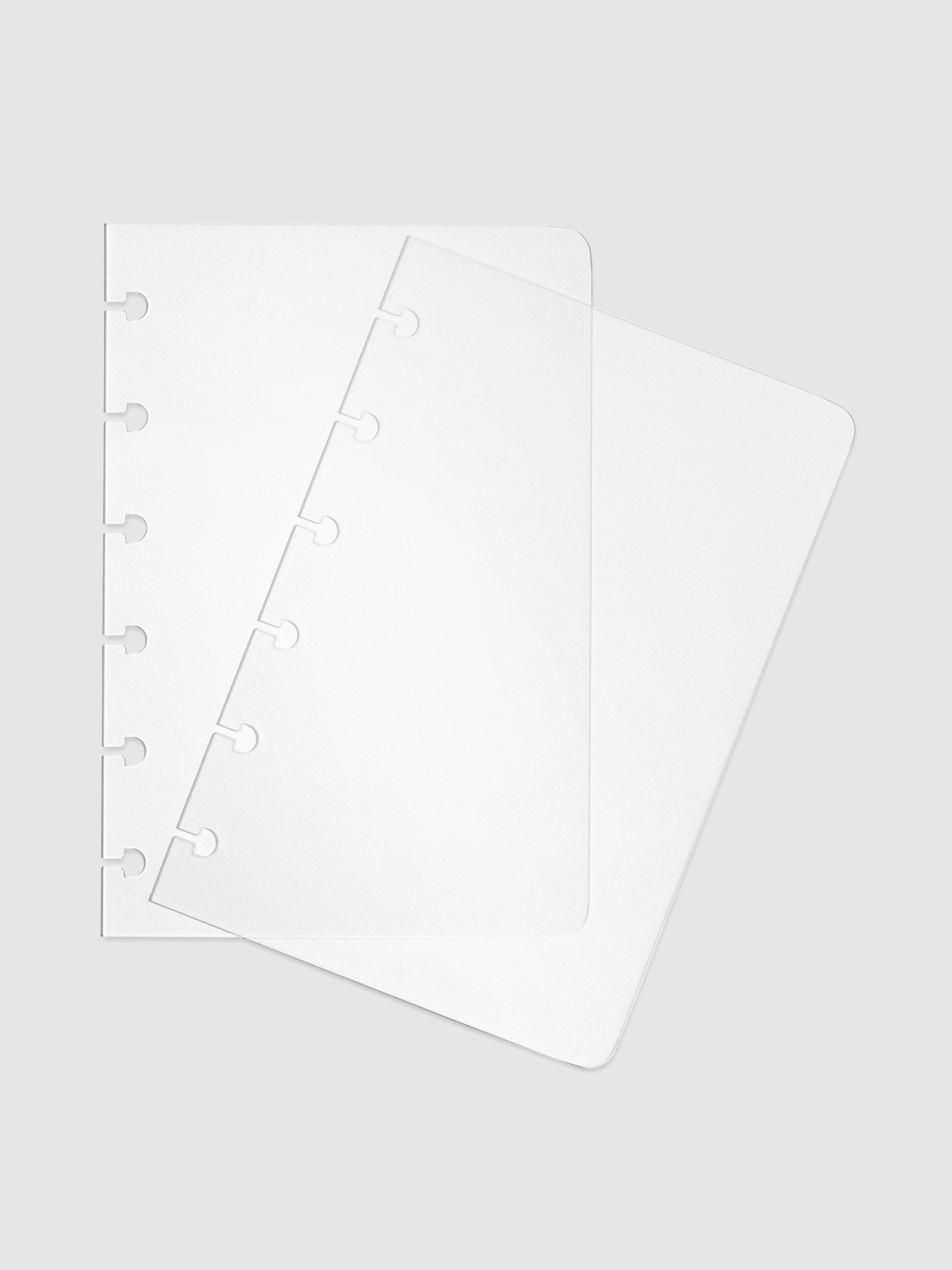 Two transparent CP Petite notebook covers laid on top of one another with the top cover tilted slightly to the right.