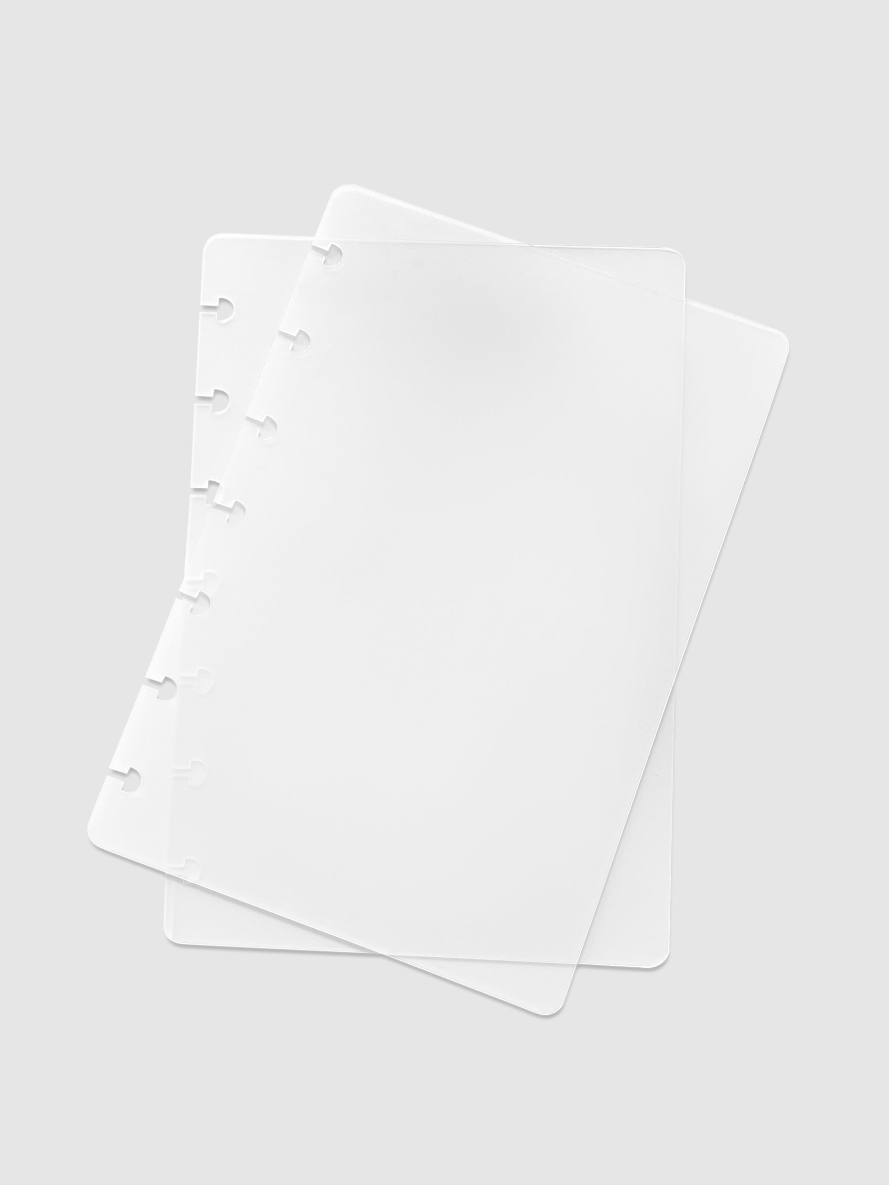 Glass Plastic Discbound Notebook Cover, HP Mini, Cloth and Paper. Two transparent notebook covers laid on top of one another with the top cover tilted slightly to the right.