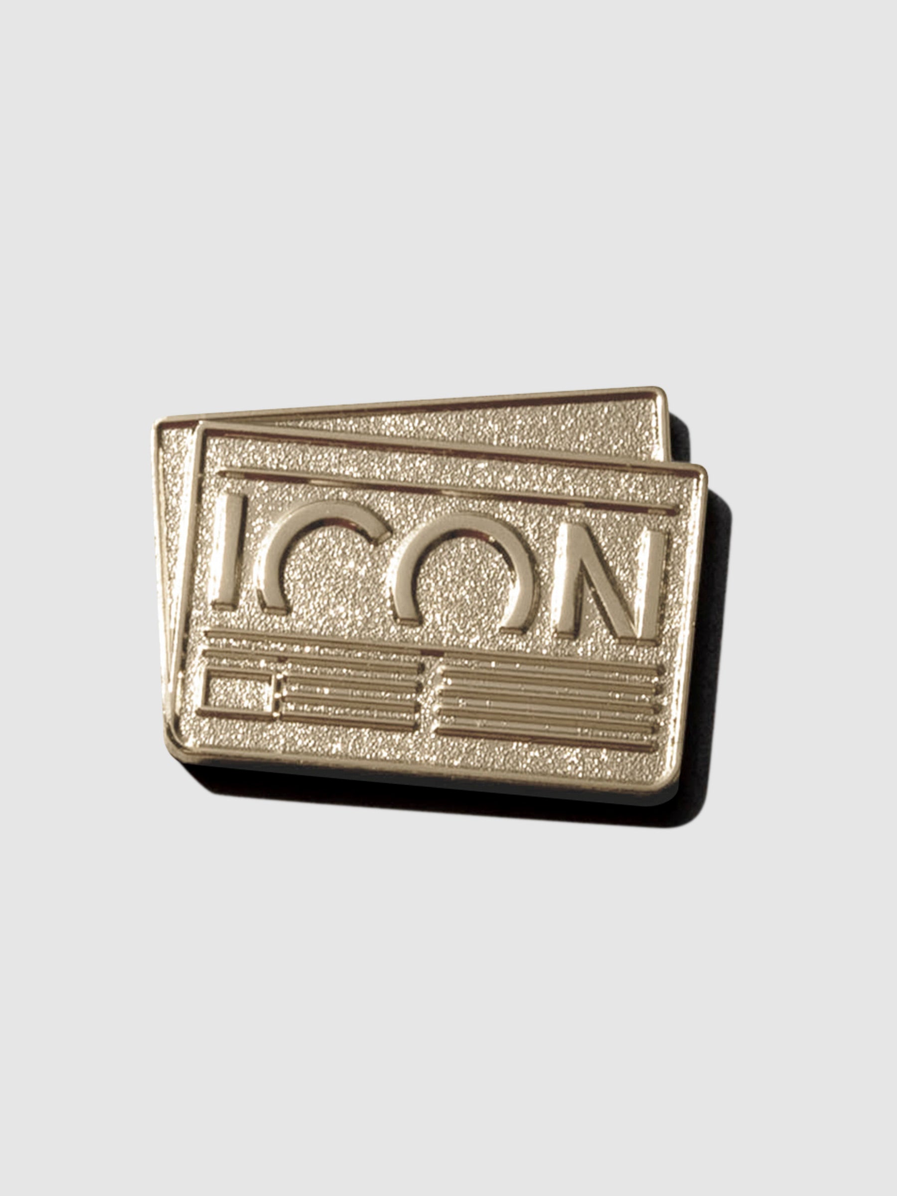 Gold pin displayed on a neutral background. Pin is shaped like a credit card with text reading "ICON" inside of it.