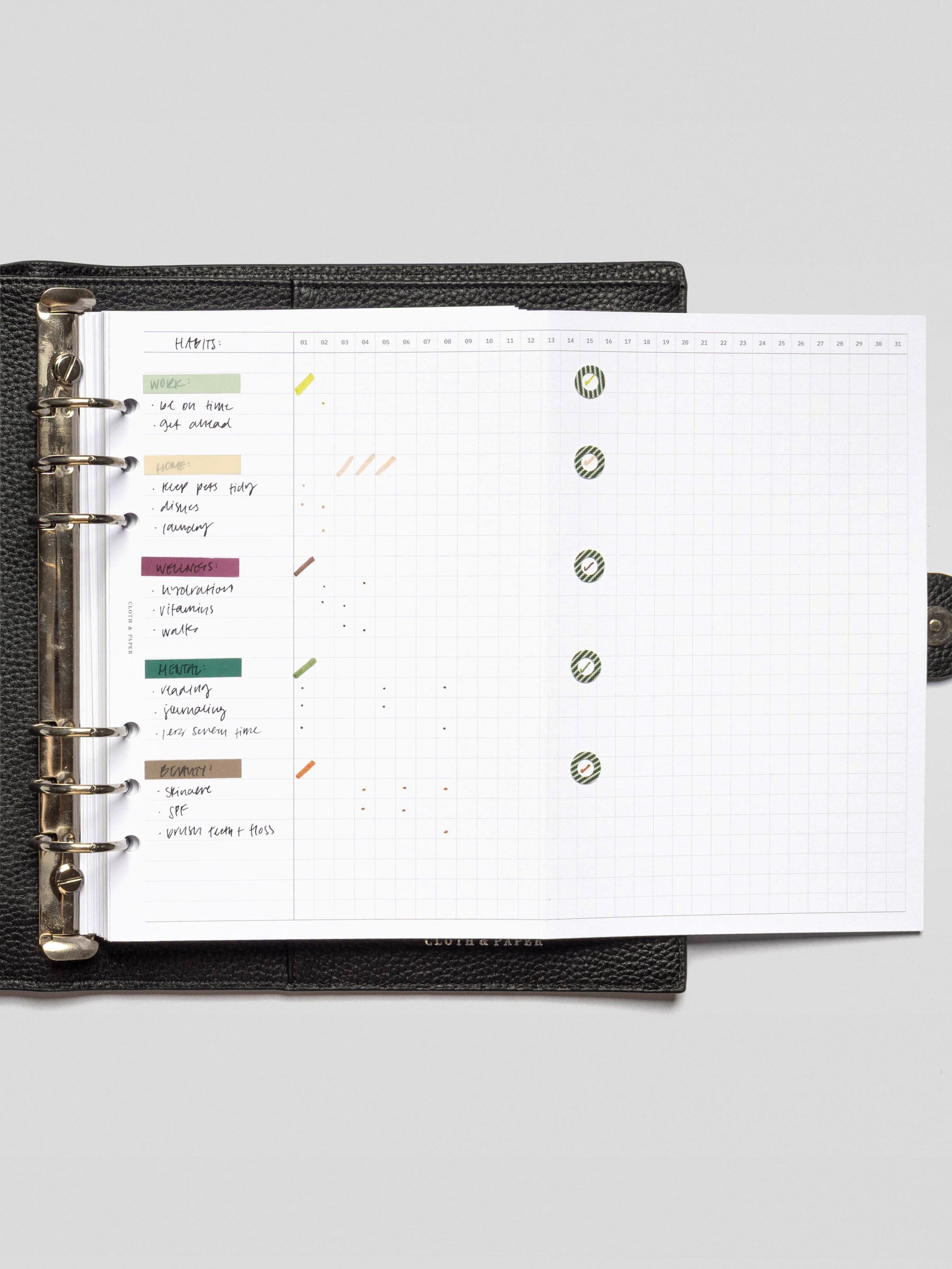 Fully open Habits Fold Out Planner Insert in A5 size inside a ring planner, displaying a grid layout filled with green spotlight stickers and handwritten tasks.