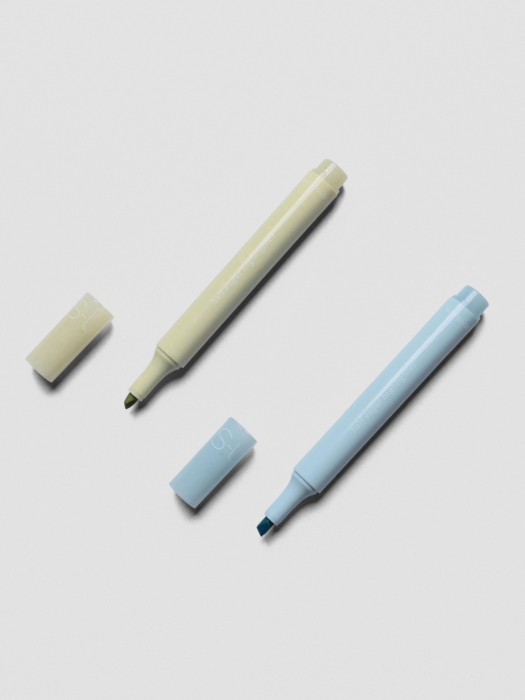 Half Sugar Highlighters shown in both Blue and Green with caps off beside the body of the highlighter.