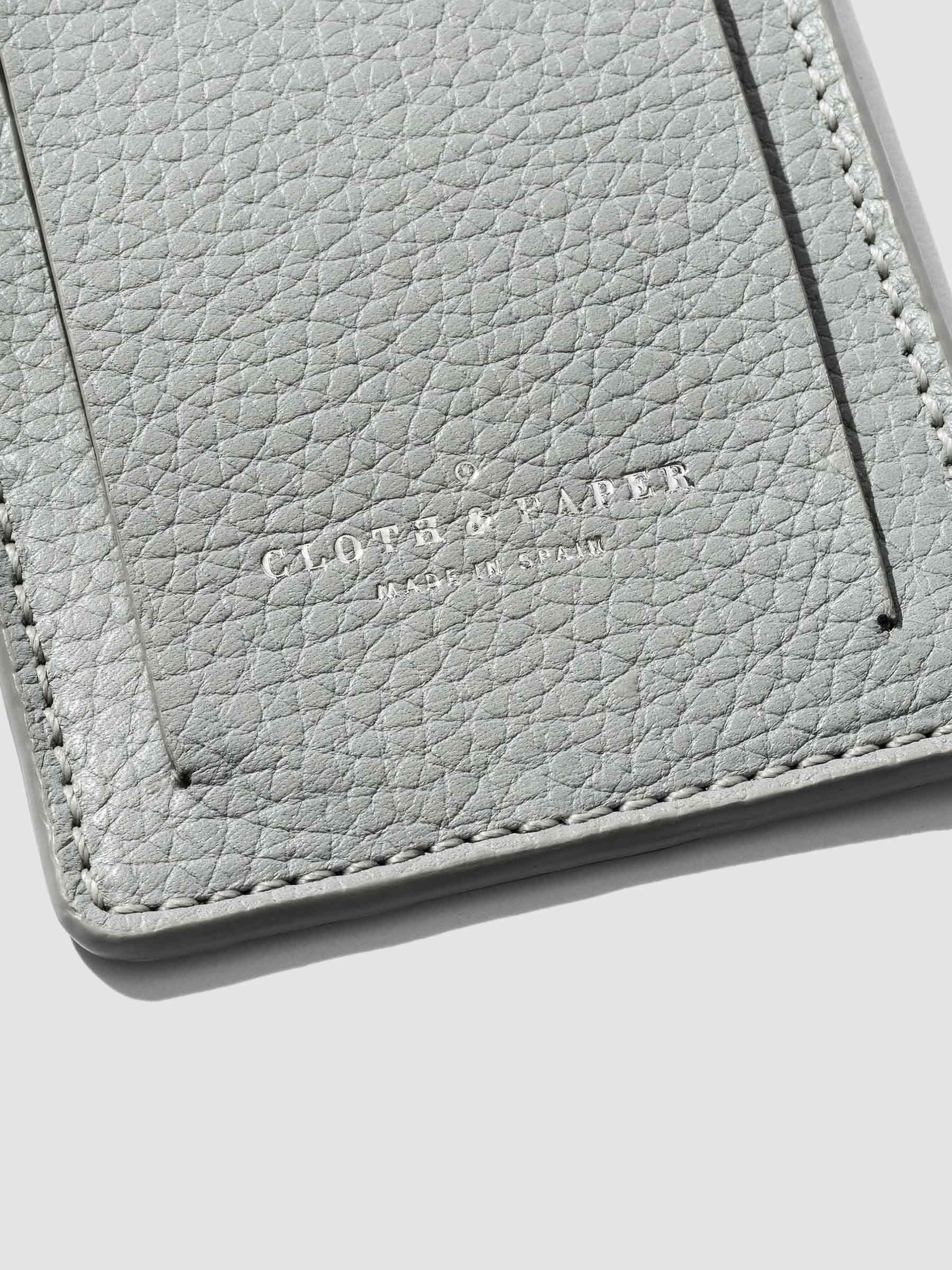 A detailed close-up of Heirloom Luggage Tag - Veleta revealing elegant embossing that reads 'Cloth & Paper,' with a subtle 'Made in Spain' inscription underneath.