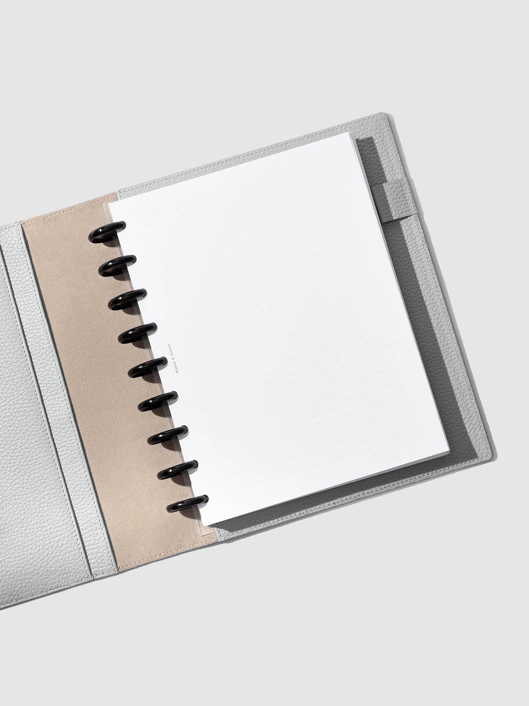 Veleta folio displayed with a discbound planner system inside of it on a neutral background.