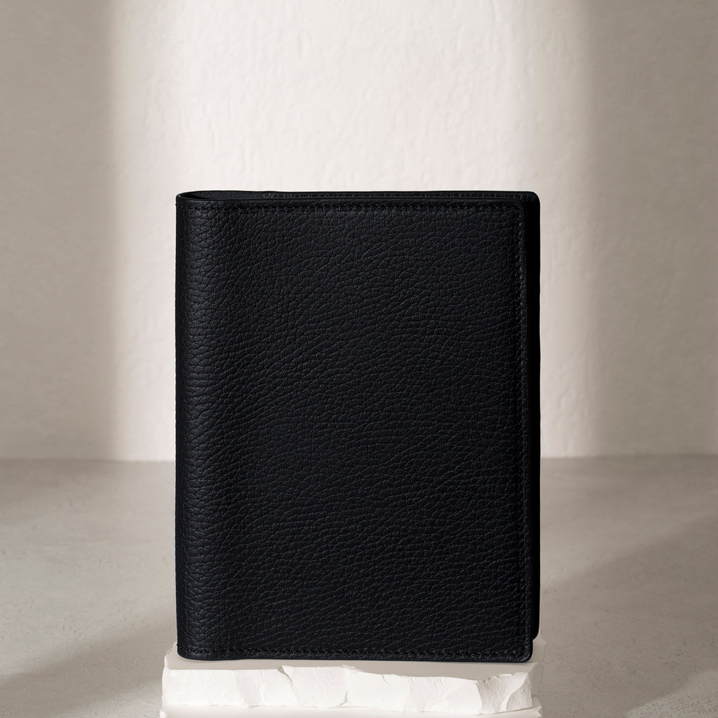 Heirloom Leather Folio, CP Petite, Cloth and Paper. Padrillo folio displayed on a white stone pedestal. The background is a natural textured off-white material, and a spotlight behind the folio highlights its placement.