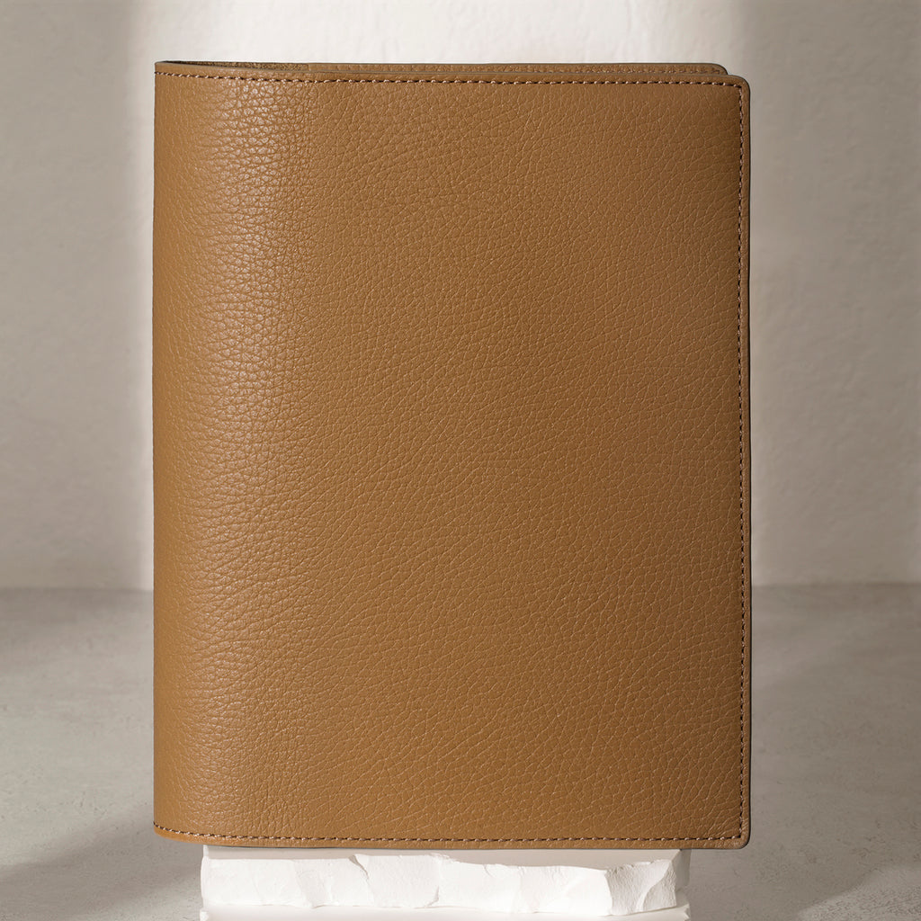 Large Catalonia folio displayed on a white stone pedestal. The background is a natural textured off-white material, and a spotlight behind the folio highlights its placement.