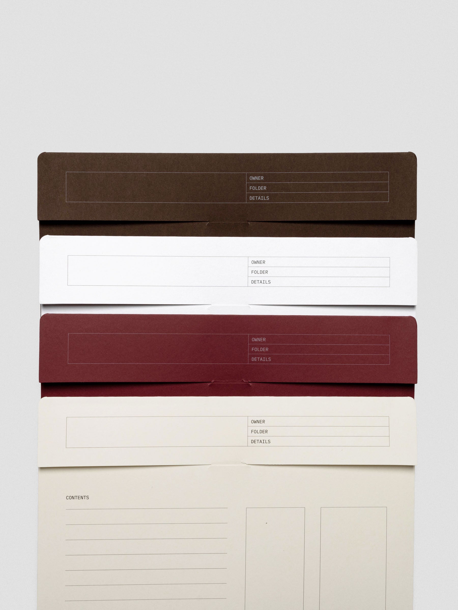 Four letter-sized index folders stacked vertically in Espresso, White, Bordeaux, and Cream, showing the labeled flap with "Owner," "Folder," and "Details" fields.
