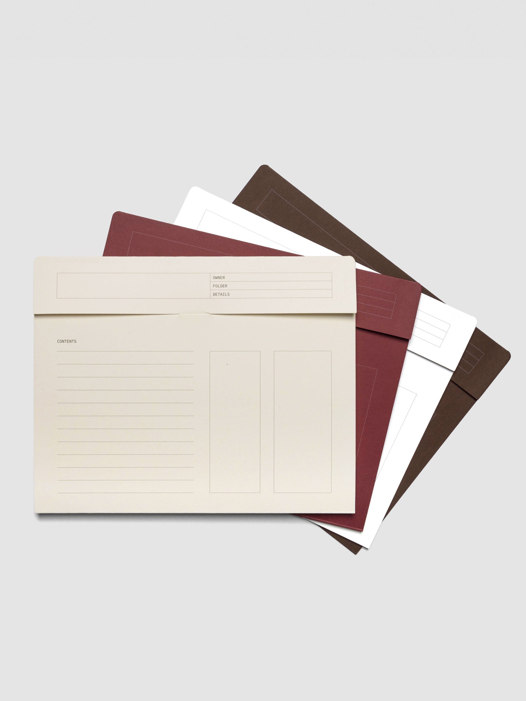 Cream index folder displayed open on top of stacked folders in Bordeaux, White, and Espresso, showing the printed contents and note fields on the folder exterior.