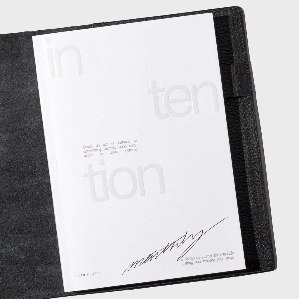 Notebook displayed in a black leather folio on a white background.