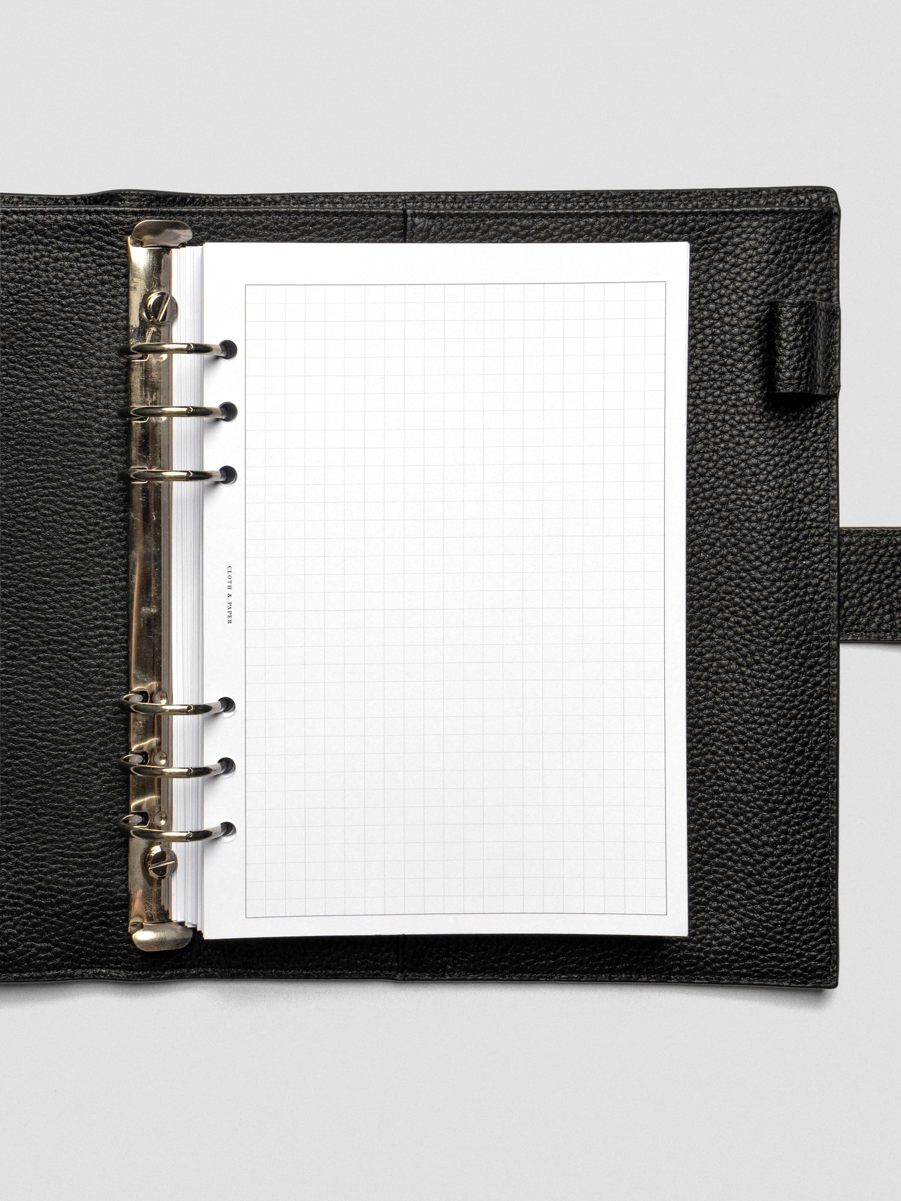 Alt Text: A single Ivy Lee Priority Planner Insert shown in an open black leather planner, featuring a blank grid layout on heavyweight white paper.