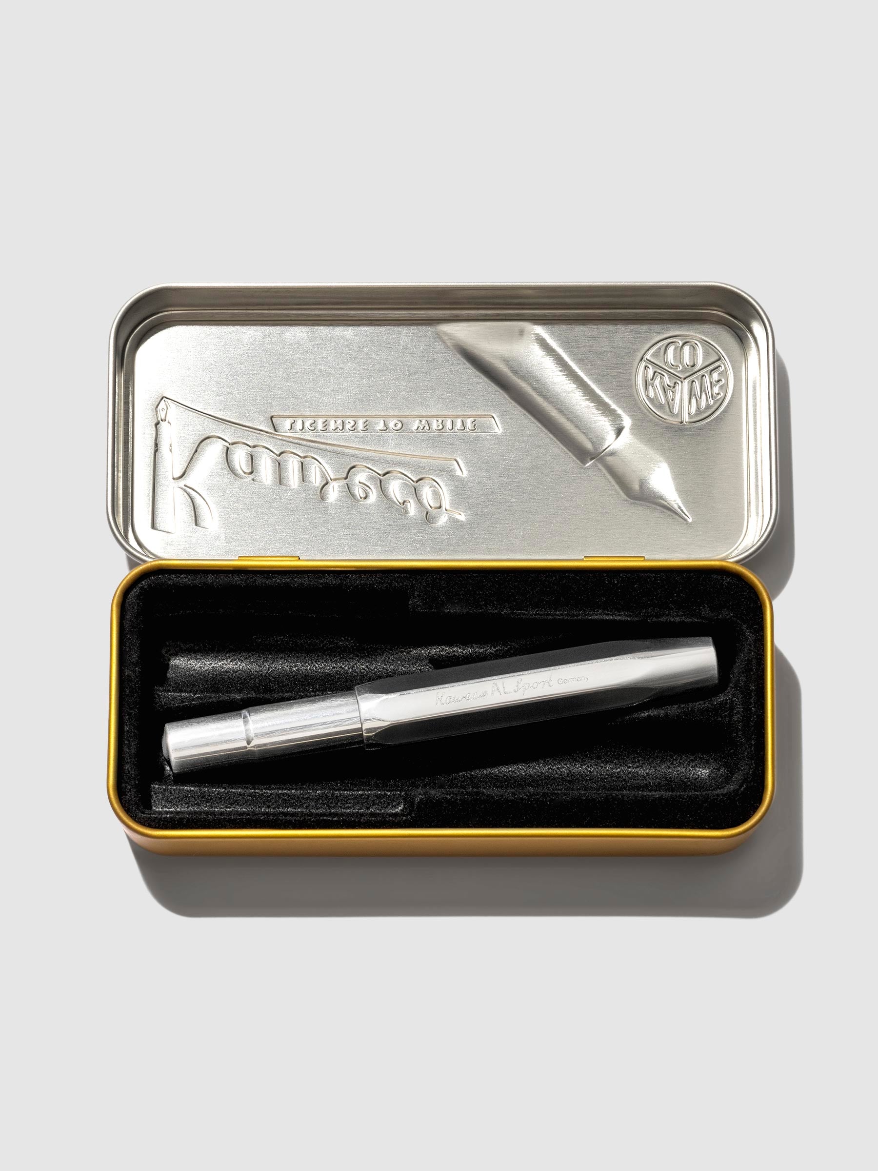 Pen displayed in its tin case on a neutral background.
