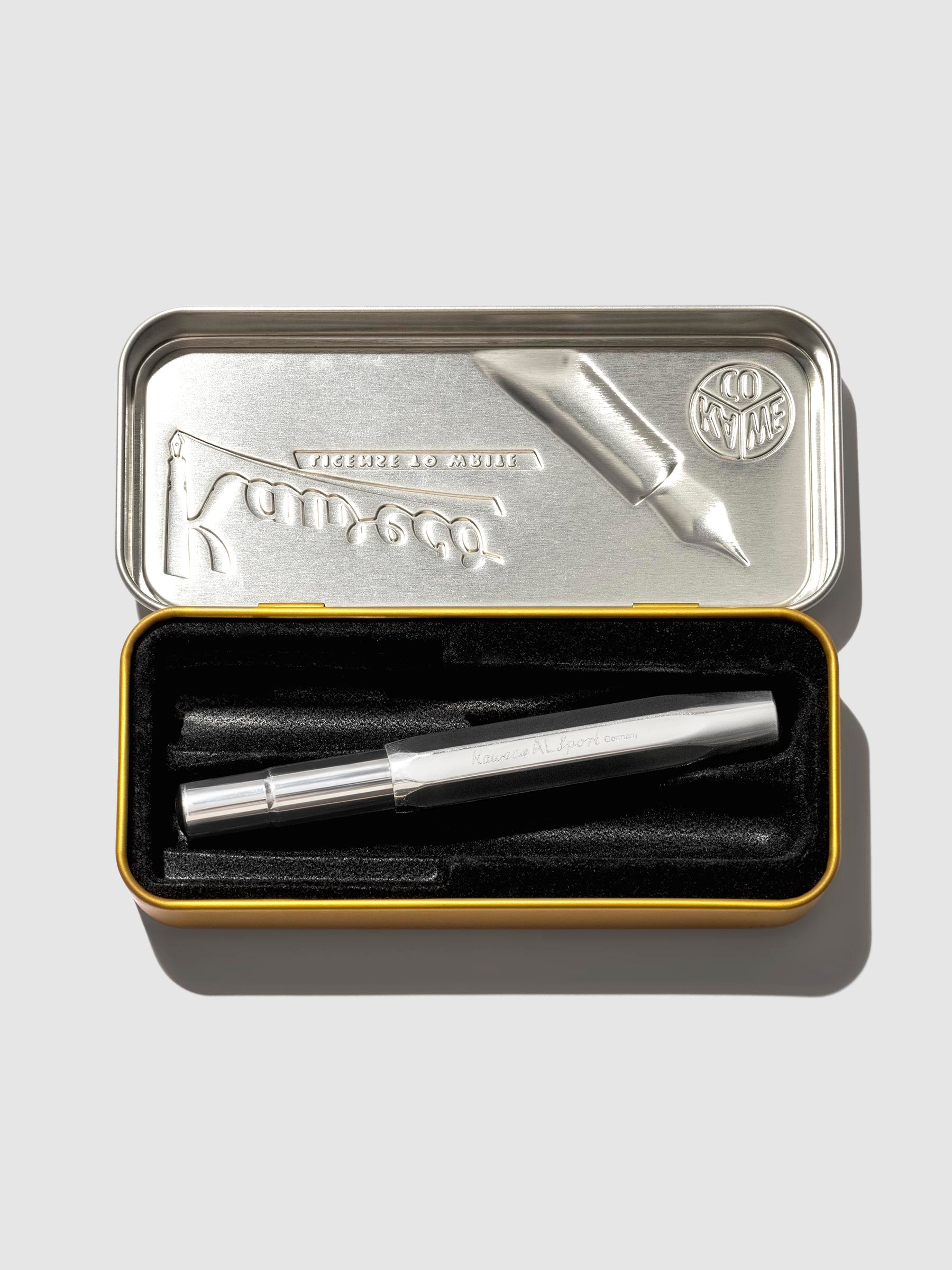 Pen displayed in its tin case on a neutral background.