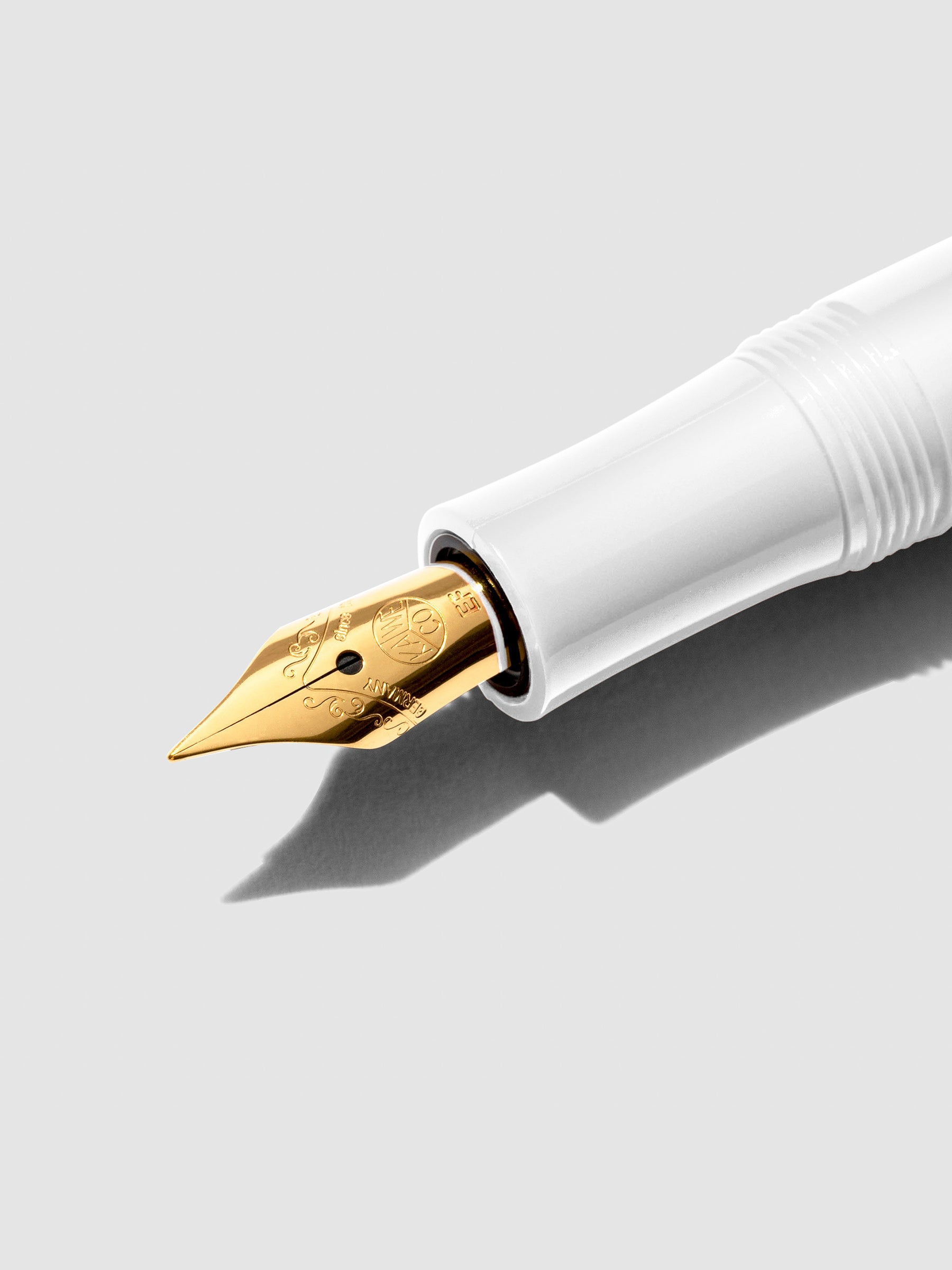 Closeup of white pen nib on a neutral background.