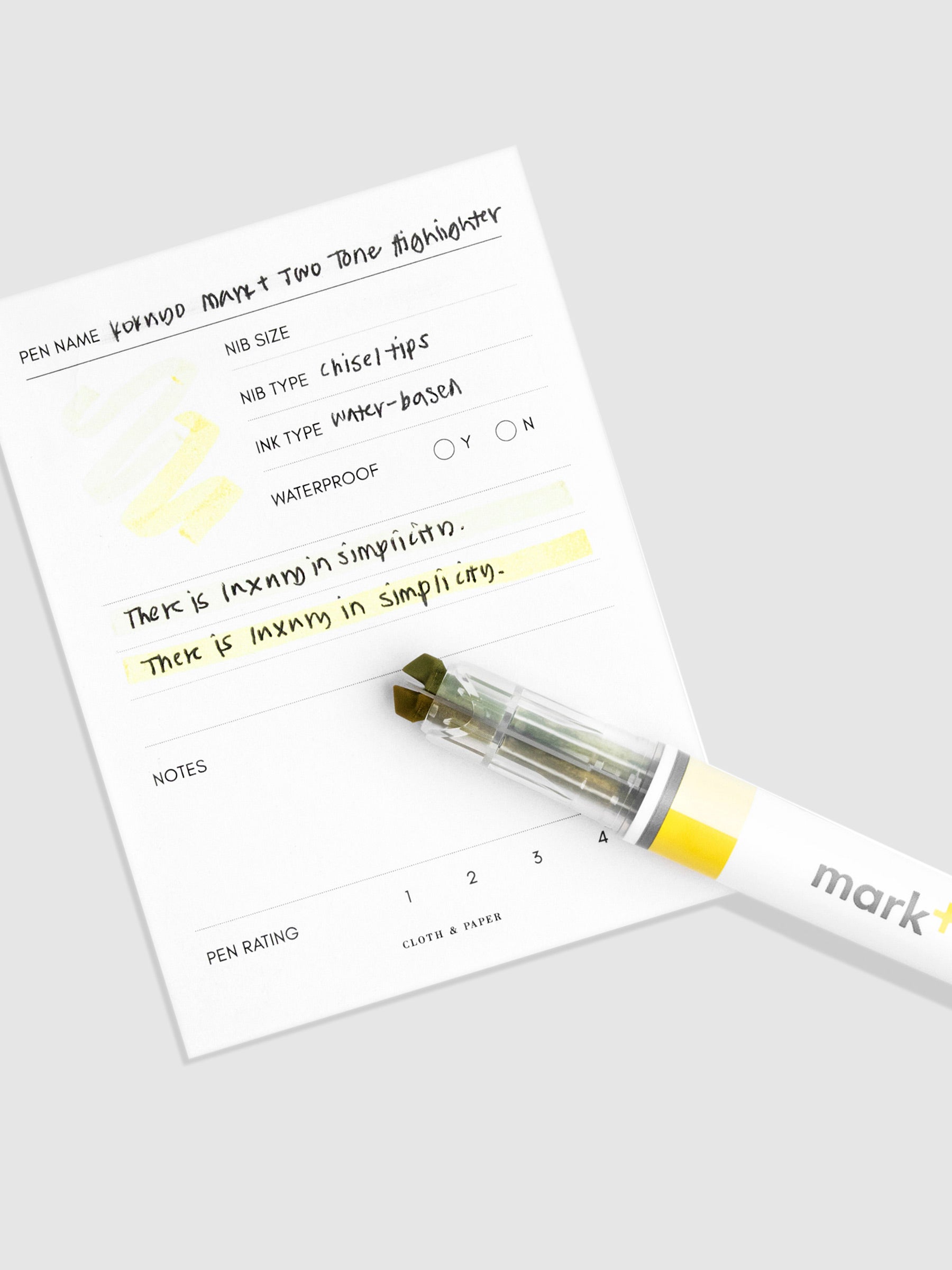 Highlighter resting on a sheet of paper displaying highlight samples from both nibs and ink colors.