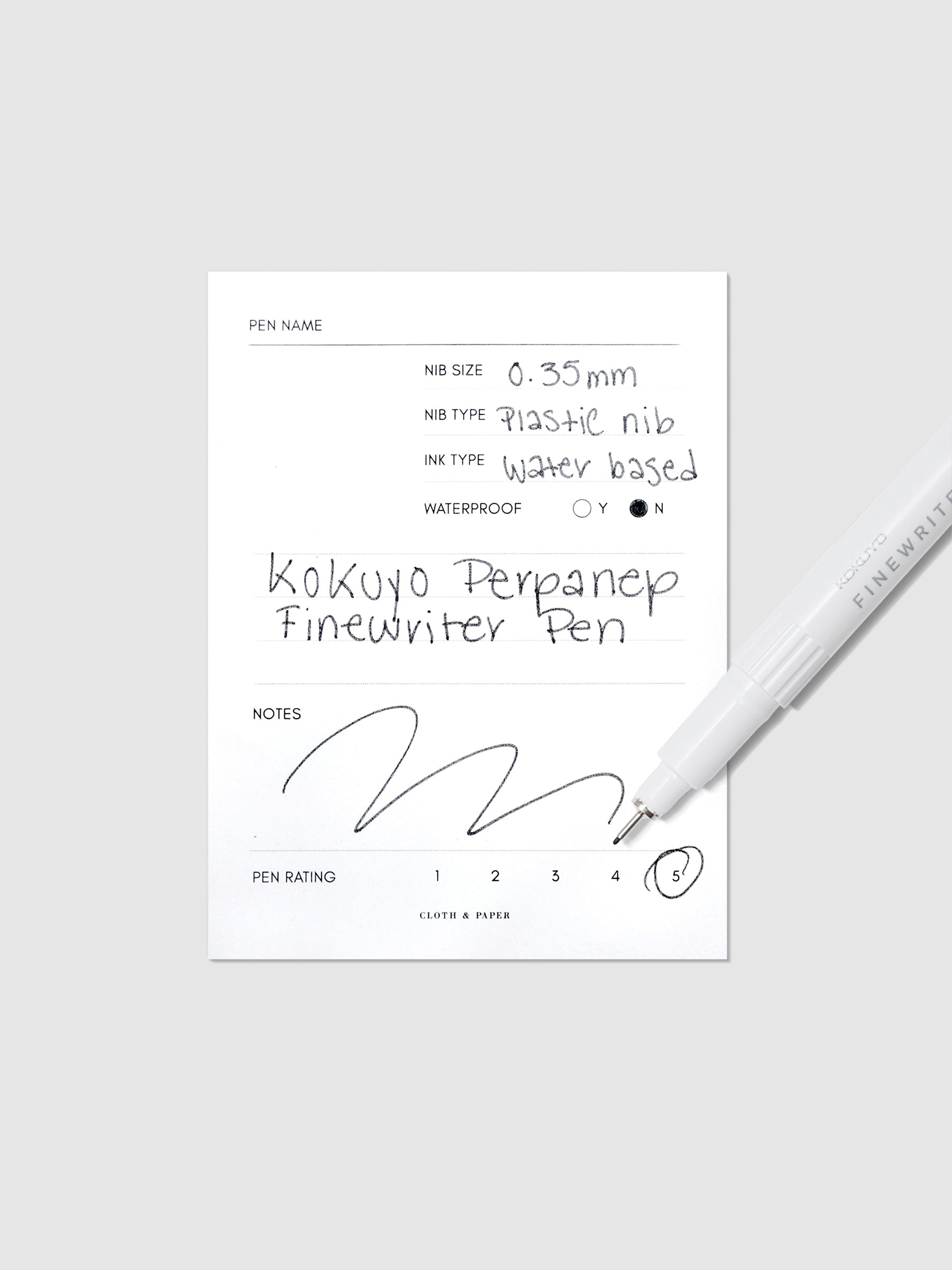 Kokuyo Perpanep Finewriter Pen, 0.35 mm, Black, Cloth and Paper. White pen with cap off tilted slightly to the left, overlapping a sample writing sheet against a neutral background. Sample sheet displays black ink writing describing pen features.