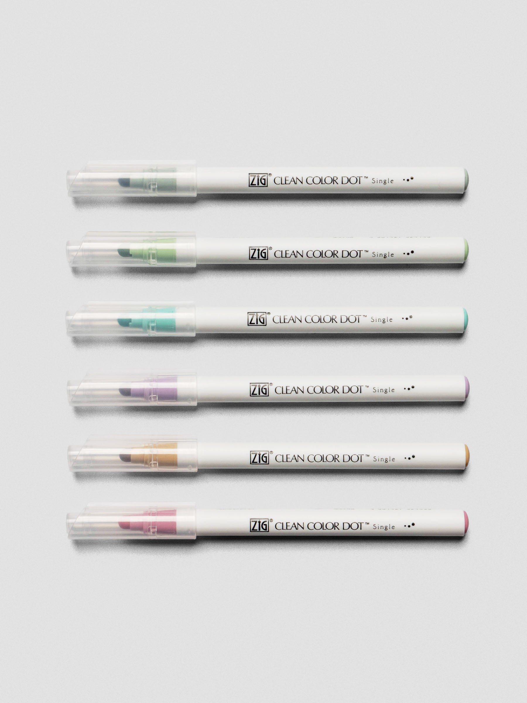 The six Kuretake ZIG Clean Color Dot Markers laid horizontally with caps on, showing the brush tips and color ends.