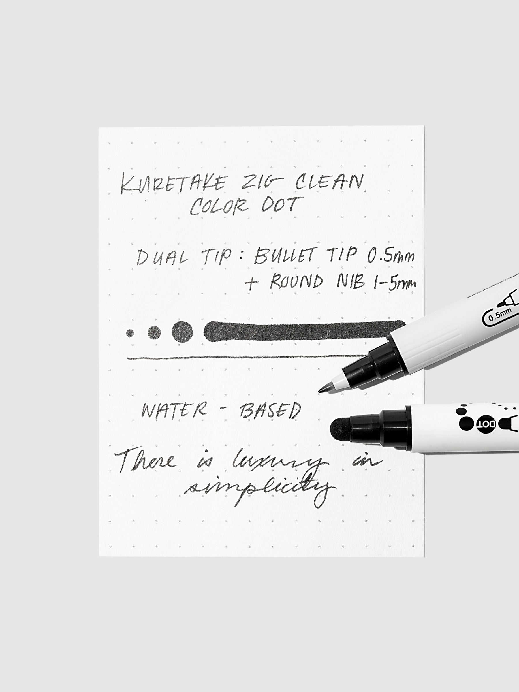 Close-up of a sample page featuring black ink from the Clean Color Dot Dual Tip Marker, demonstrating thin lines and various dot sizes with both tips in view.