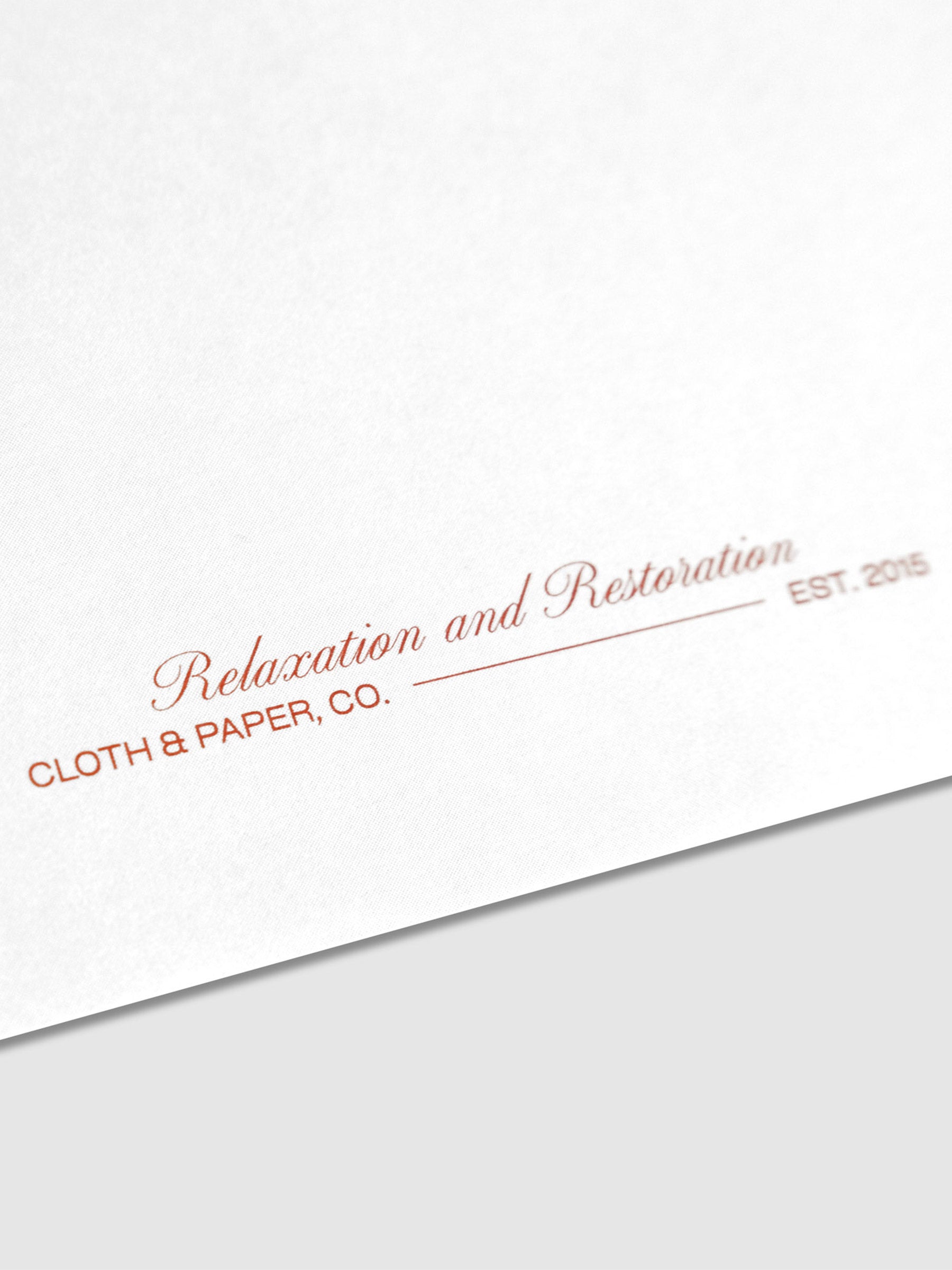 Closeup of red text on card that reads "Relaxation and Restoration / Cloth & Paper Co / Est. 2015"